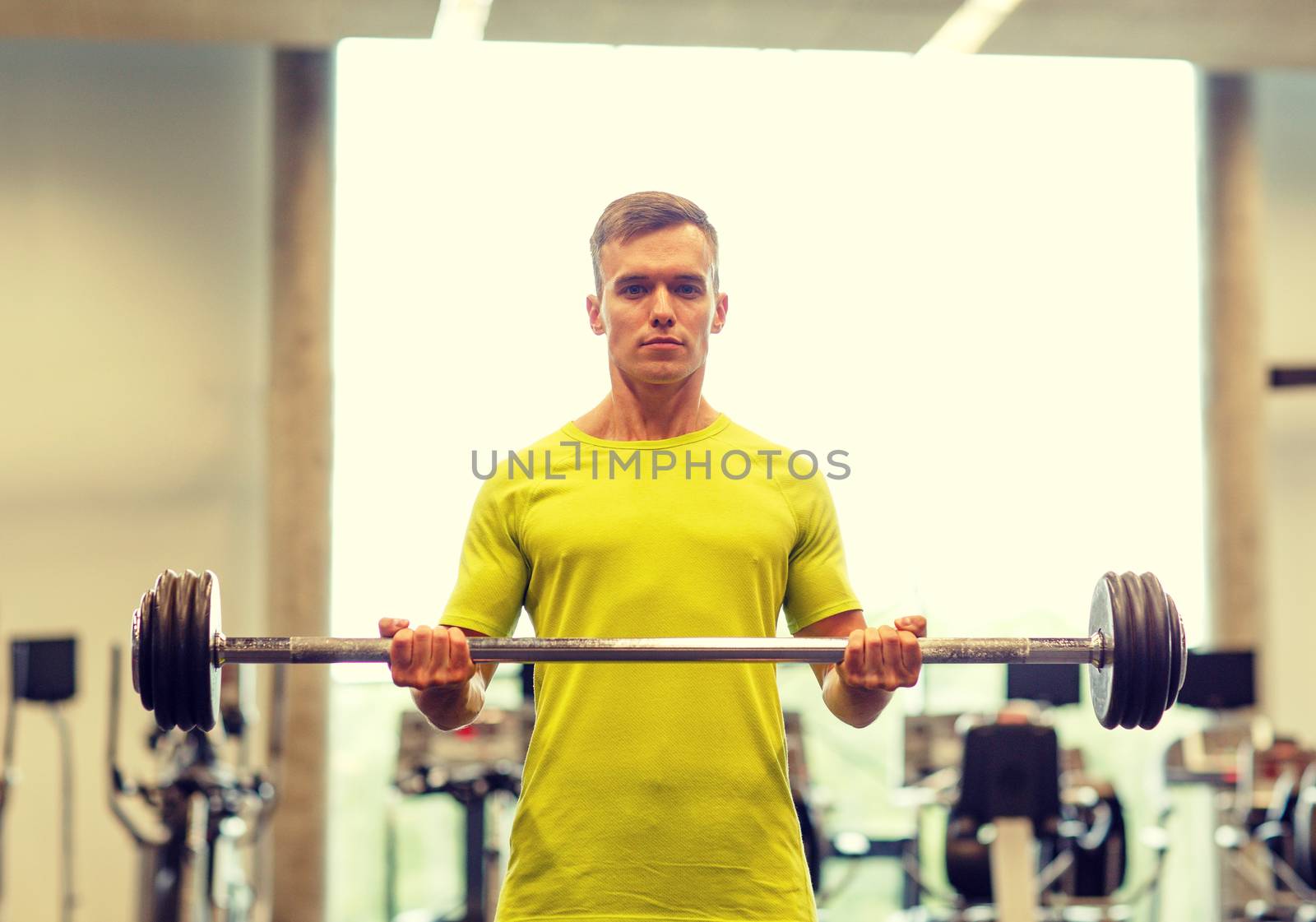 man doing exercise with barbell in gym by dolgachov