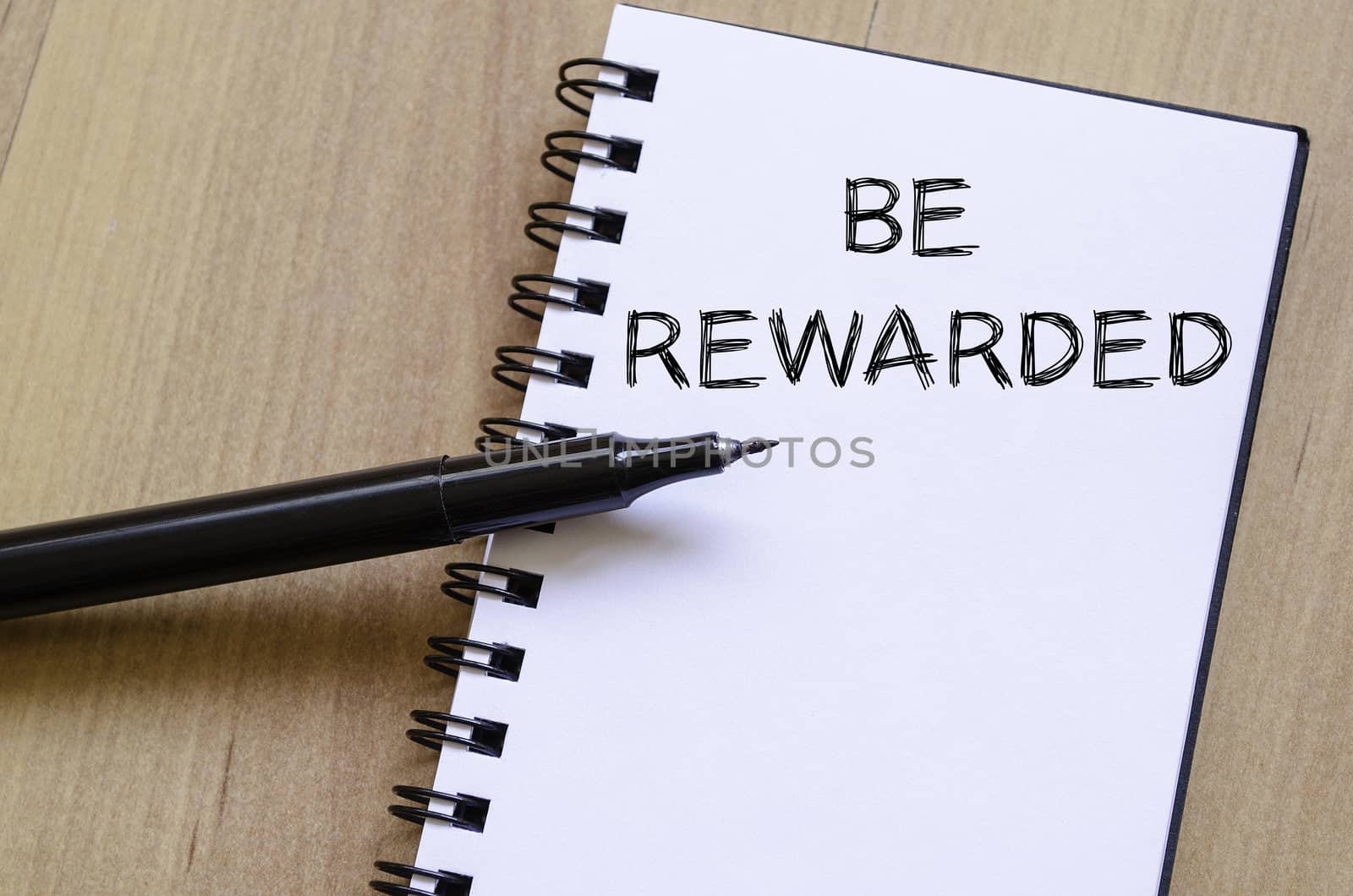 Be rewarded text concept write on notebook with pen