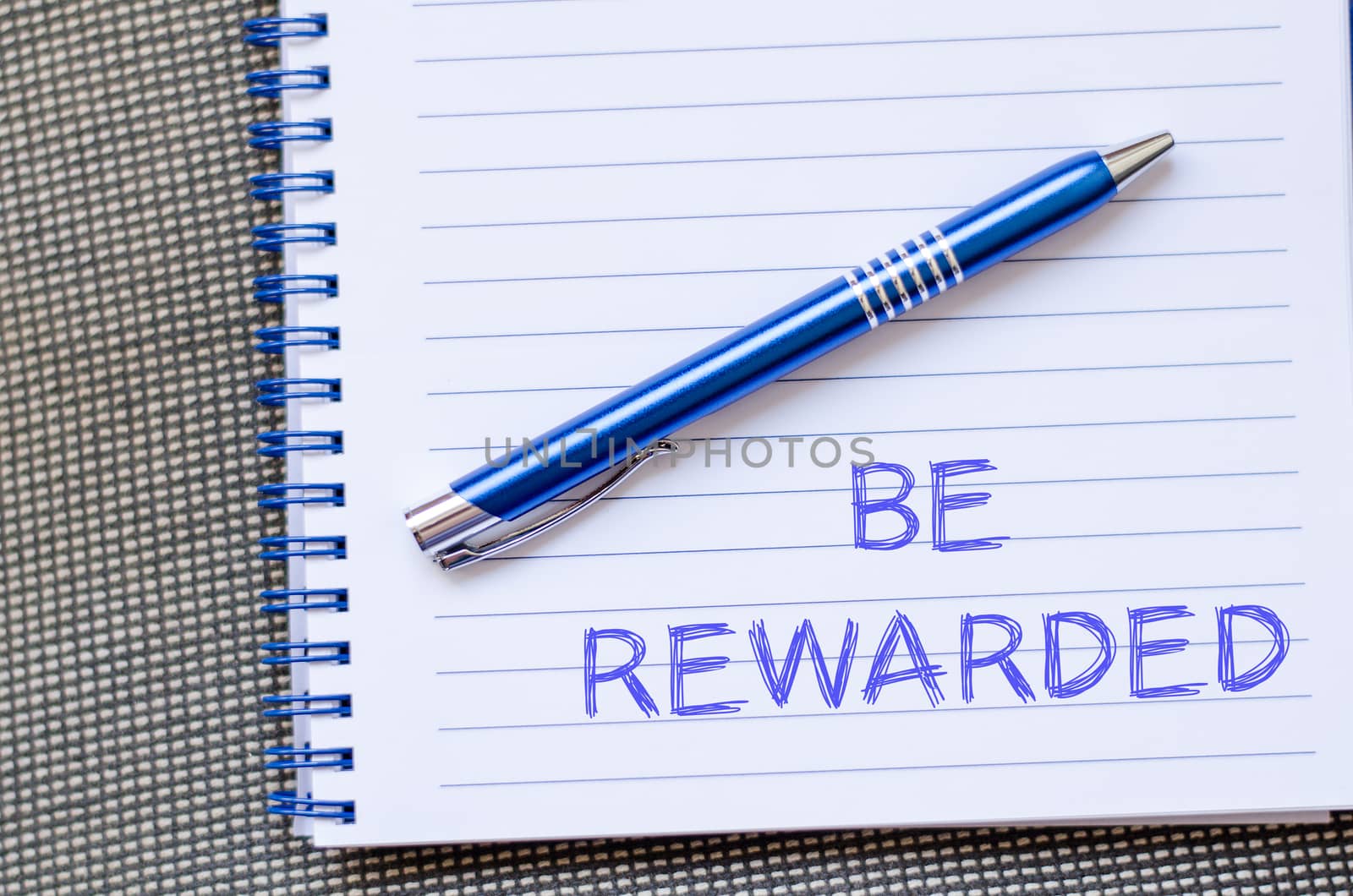 Be rewarded text concept write on notebook with pen