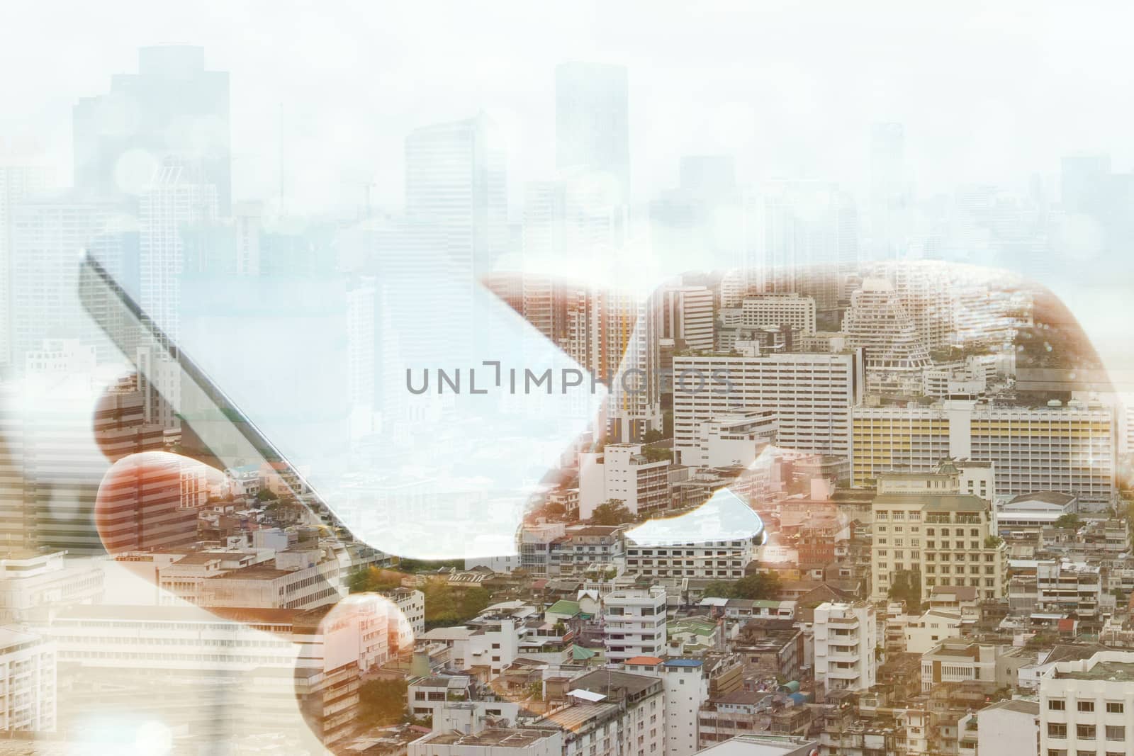 Double exposure of cityscape and smart phone, business technology concept.