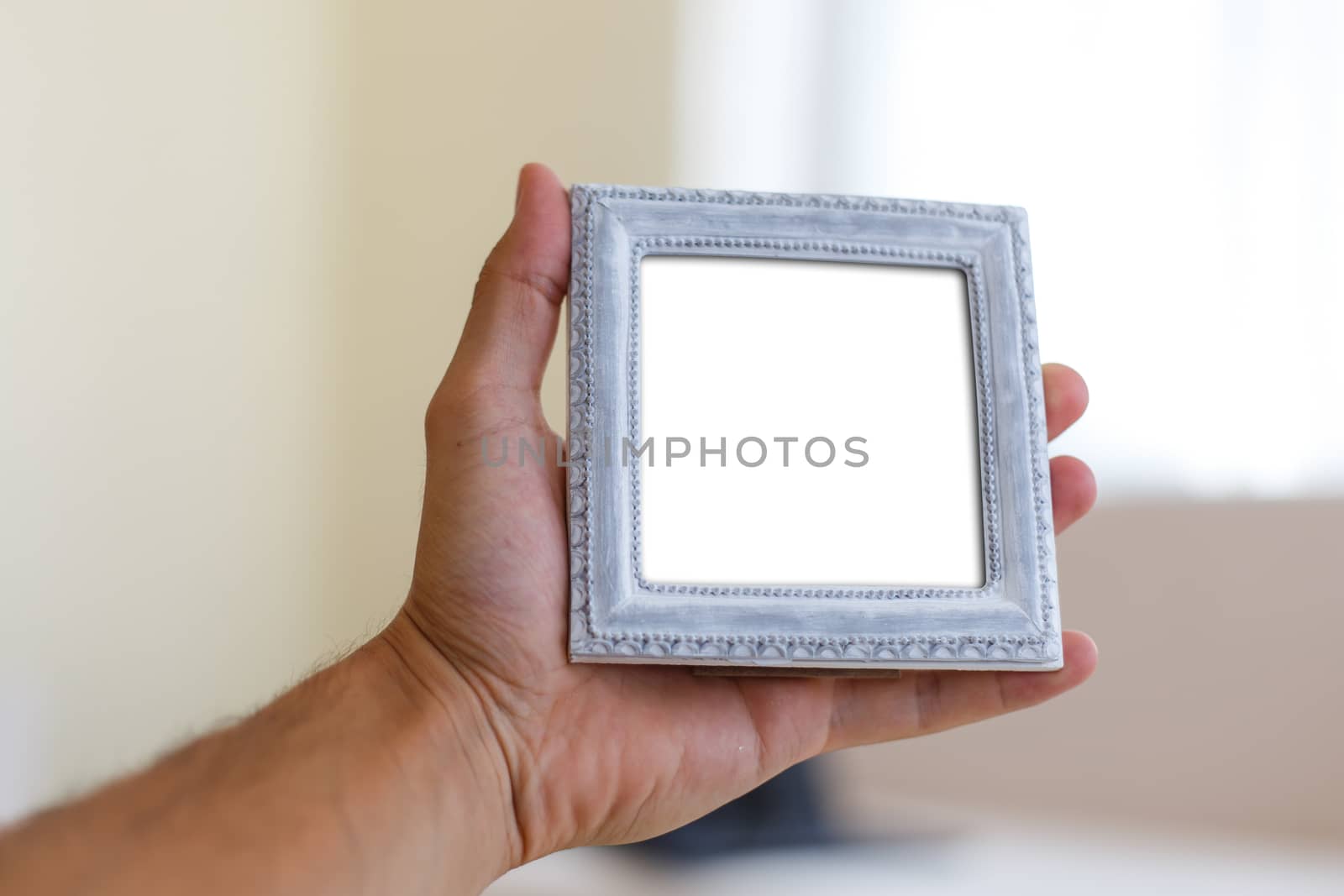 Close up detailed front view of white blank wooden frame with copy space, holding on man hand.
