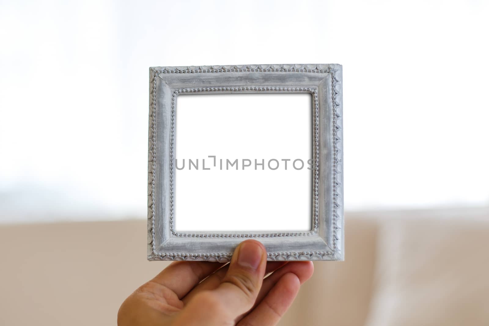 Close up detailed front view of white blank wooden frame with copy space, holding on man hand.