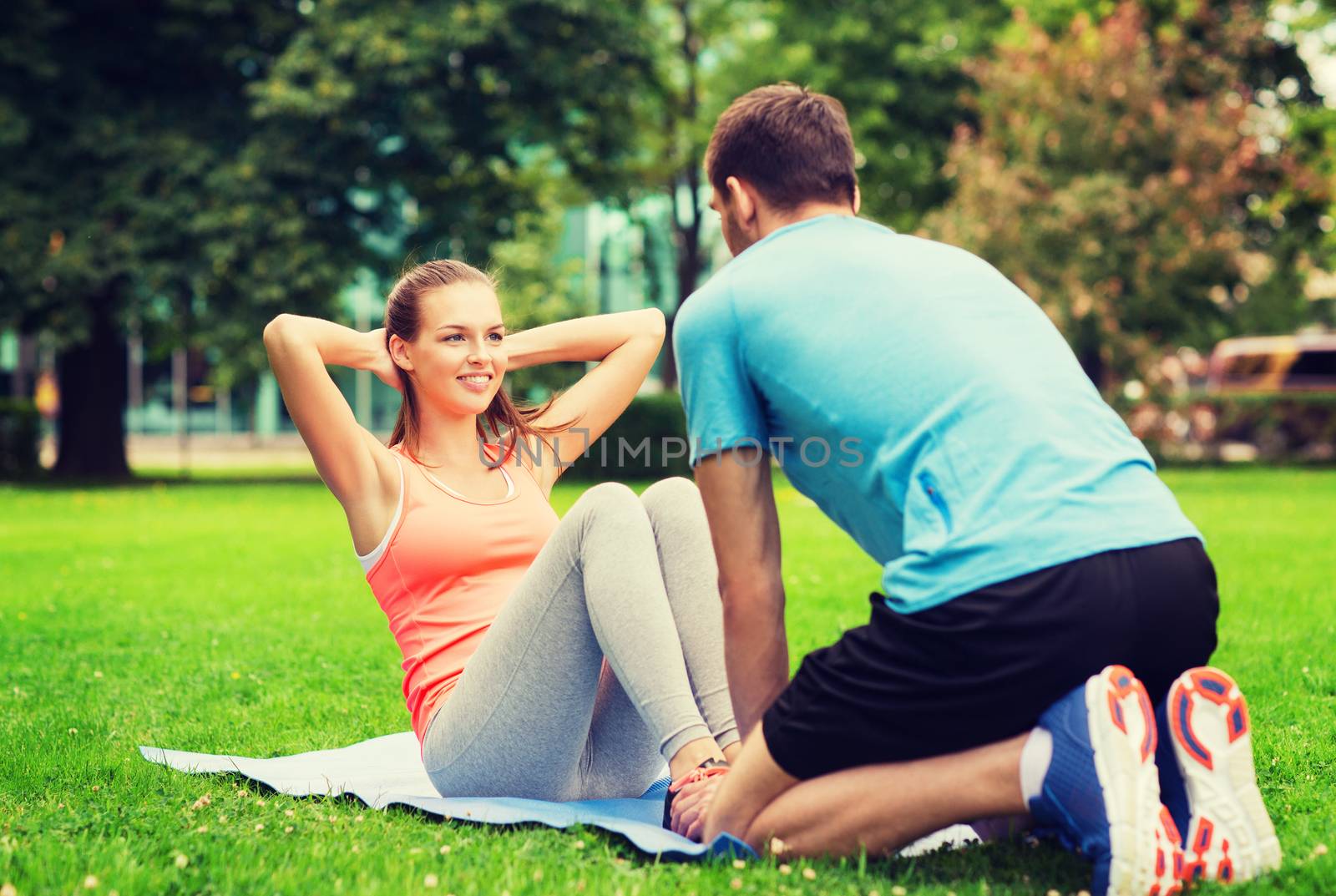 smiling woman doing exercises on mat outdoors by dolgachov