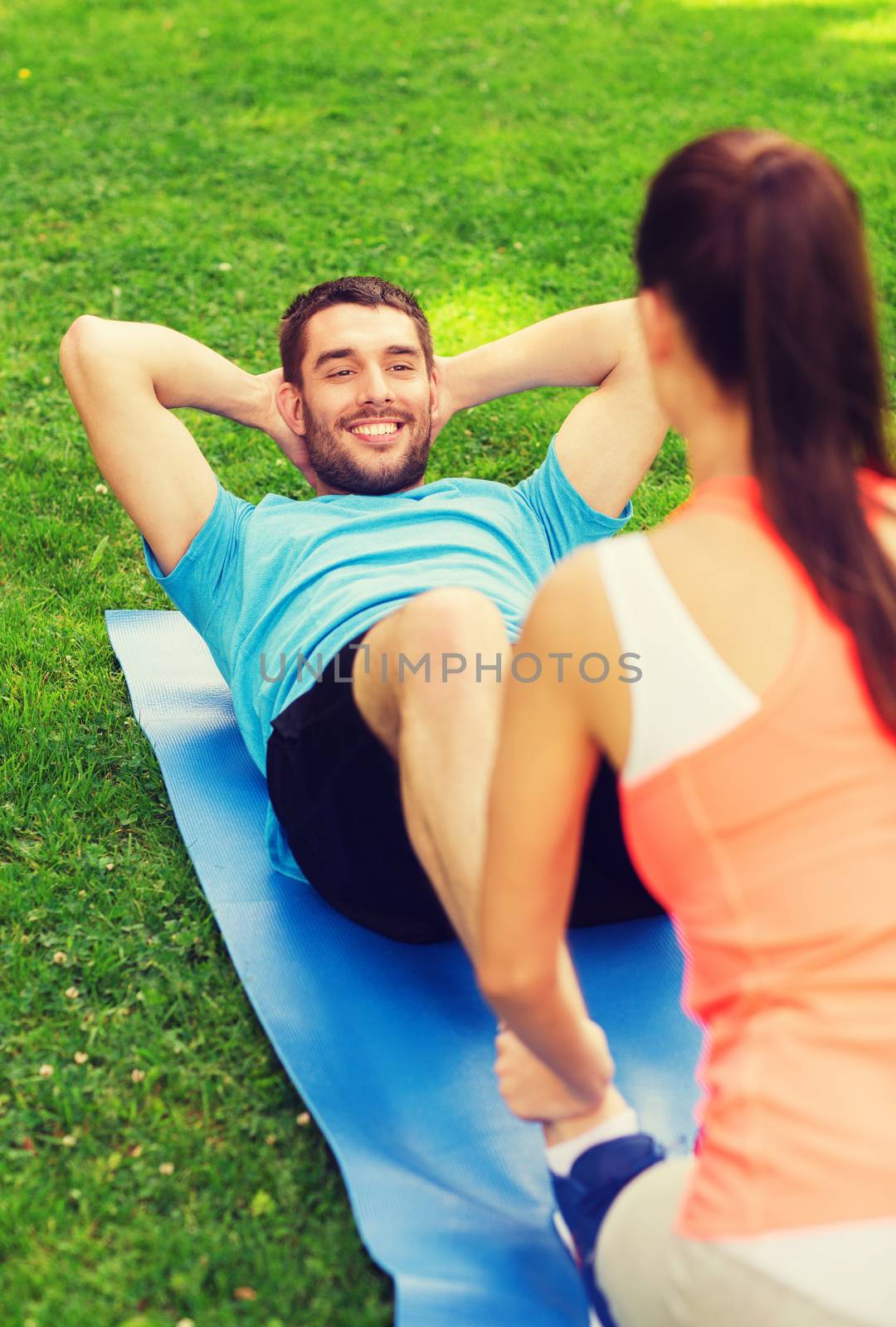 fitness, sport, training, teamwork and lifestyle concept - smiling man with personal trainer doing exercises on mat outdoors