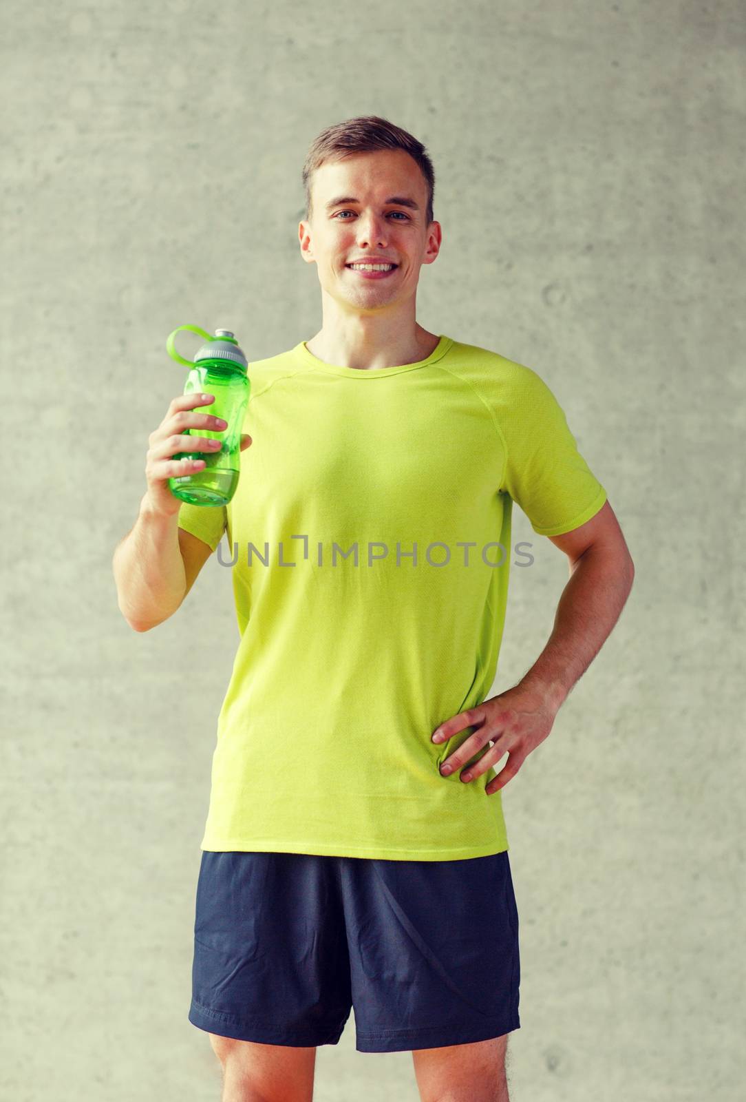 smiling man with bottle of water in gym by dolgachov