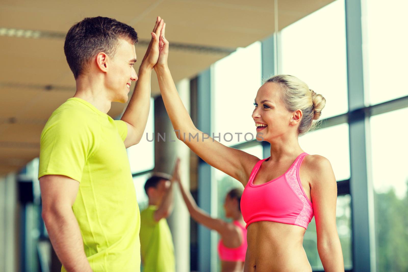smiling man and woman making high five in gym by dolgachov