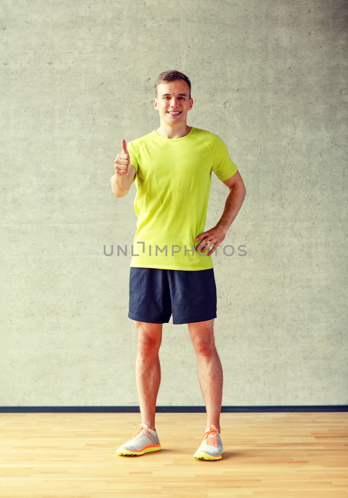 sport, fitness, lifestyle and people concept - smiling man showing thumbs up in gym