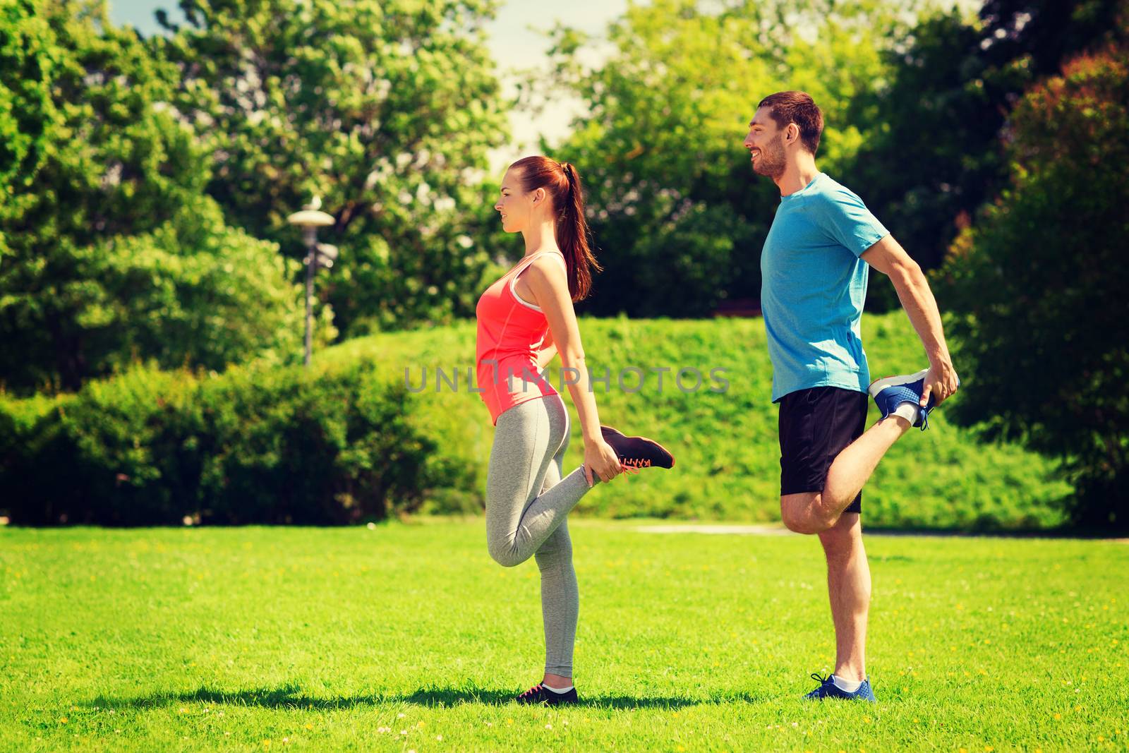 fitness, sport, training and lifestyle concept - smiling couple stretching outdoors