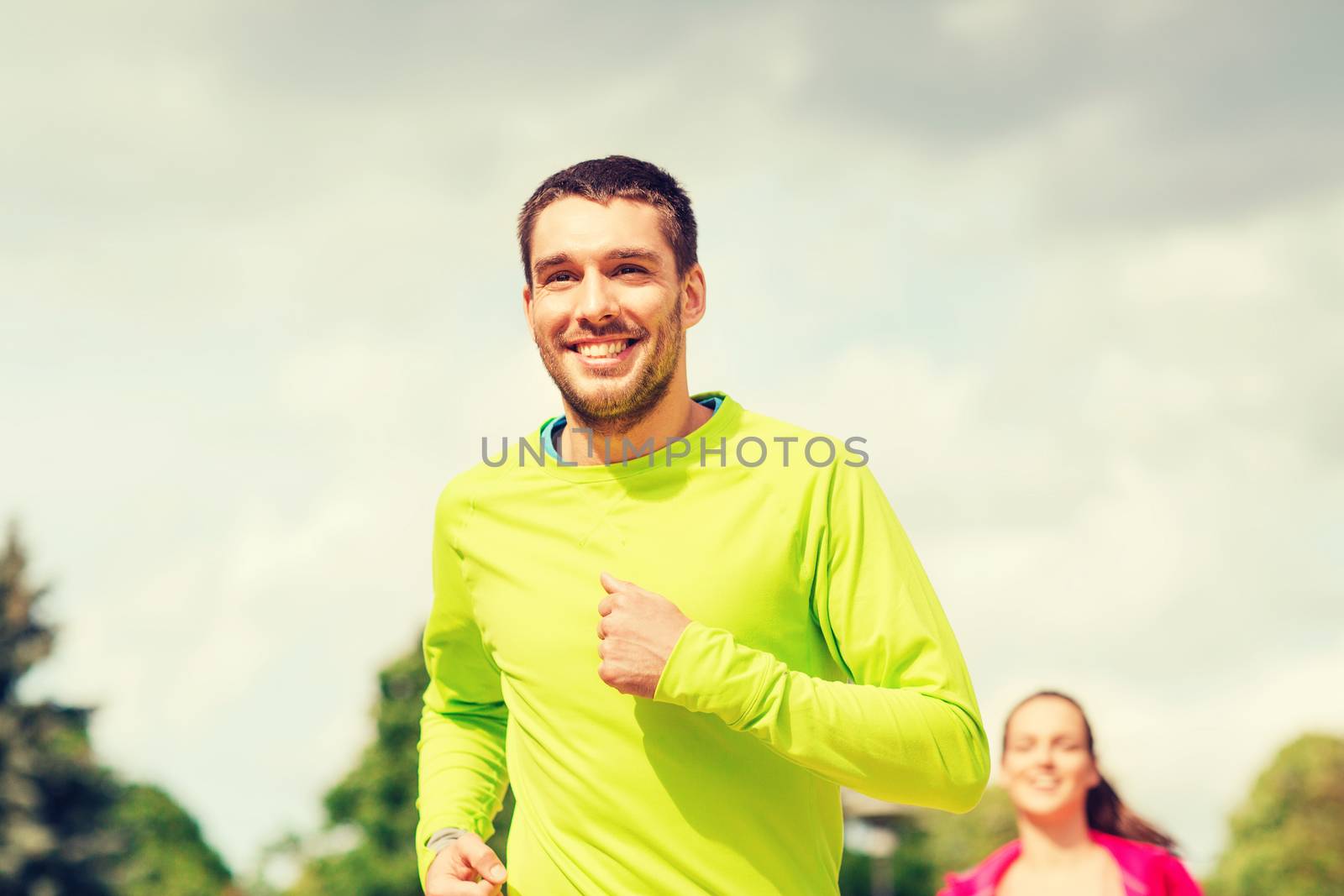 fitness, sport, friendship and lifestyle concept - smiling couple running outdoors