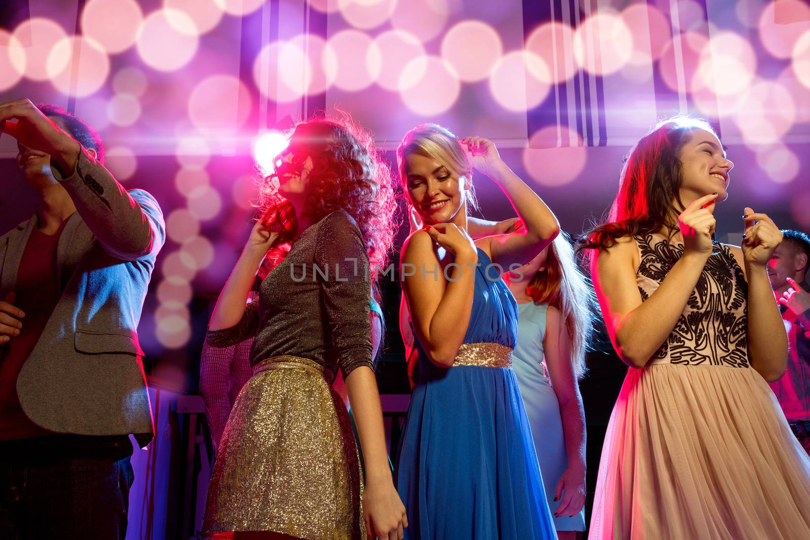 smiling friends dancing in club by dolgachov