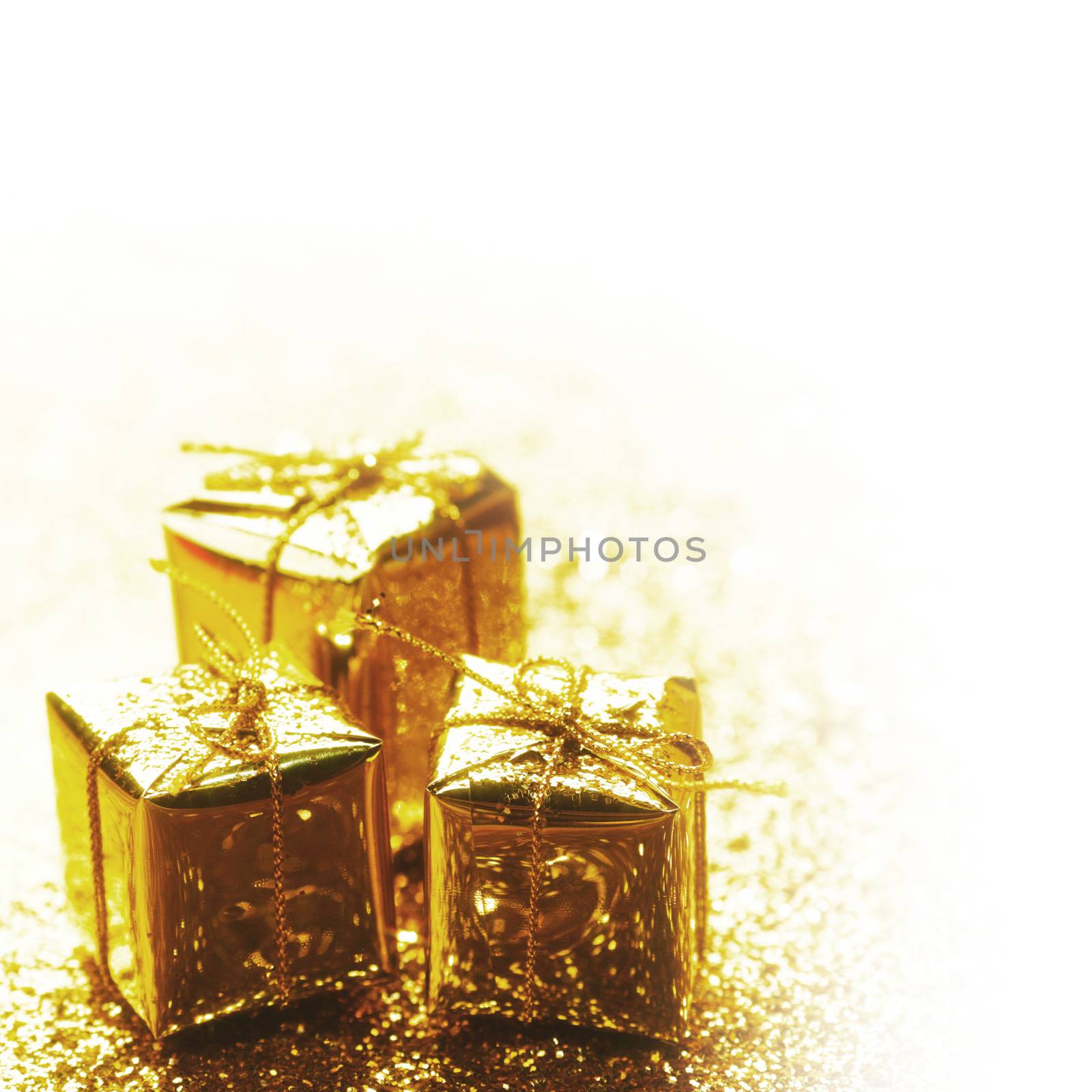 Gold decorative boxes with holiday gifts on abstract gold background with white copy space