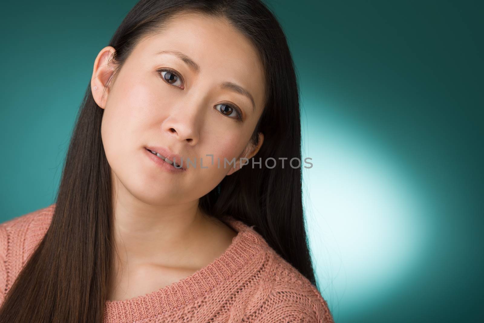 A headshot of a Japanese woman in hear early 30s on a simple green background.