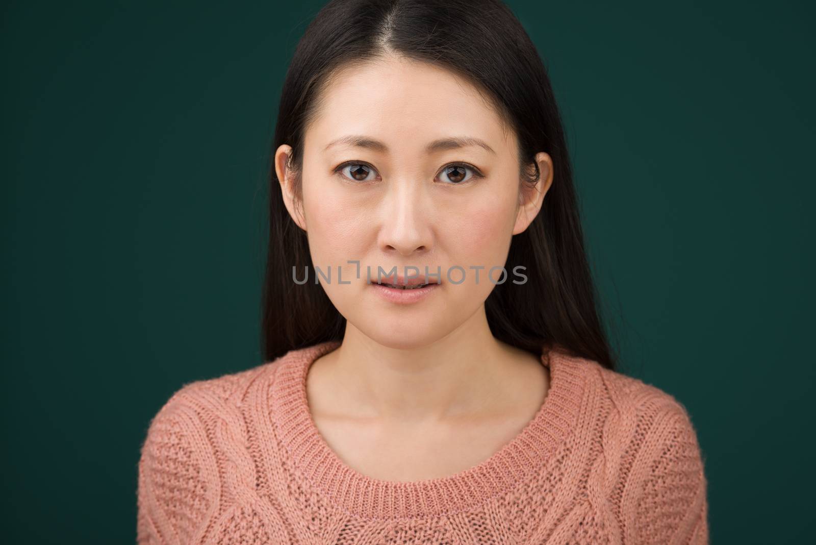 A headshot of a Japanese woman in hear early 30s on a simple green background.