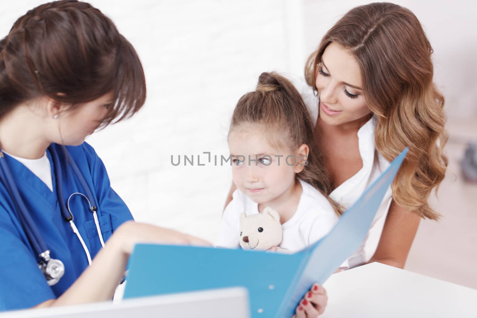 Young pediatrician doctor talking with girl and her mother