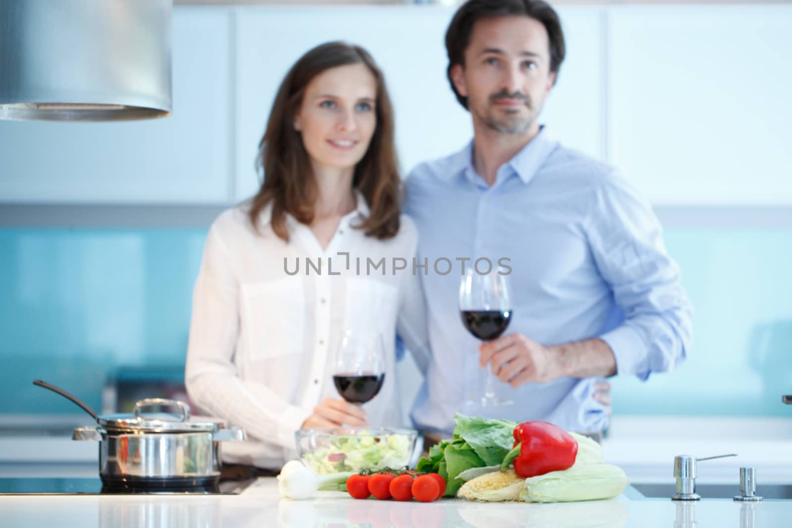 Portrait of a couple having a glass of red wine while cooking dinner