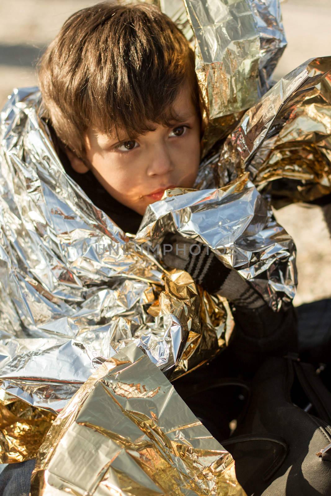 GREECE, Lesbos: A refugee child is wrapped in a heat blanket on the Greek island of Lesbos on December 6, 2015.  Many of the boats and rafts continue to make the journey from Turkey to Greece each day as thousands flee conflict in Iraq, Afghanistan, Syria and other countries. 