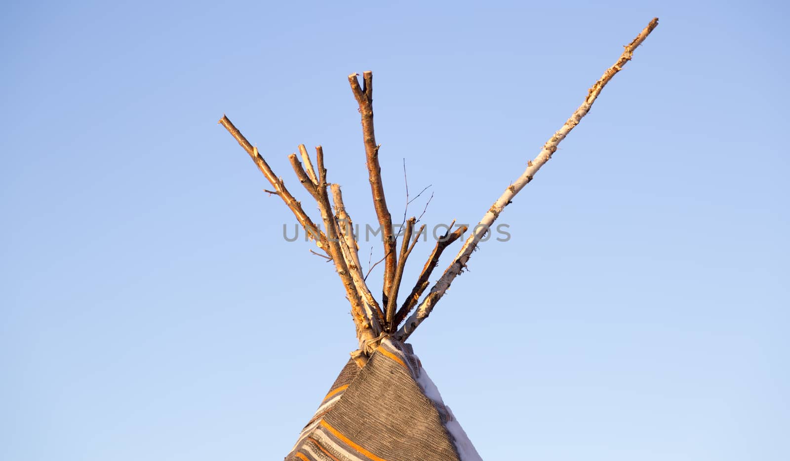 Top of a Tipi with a clear blue sky behind it.