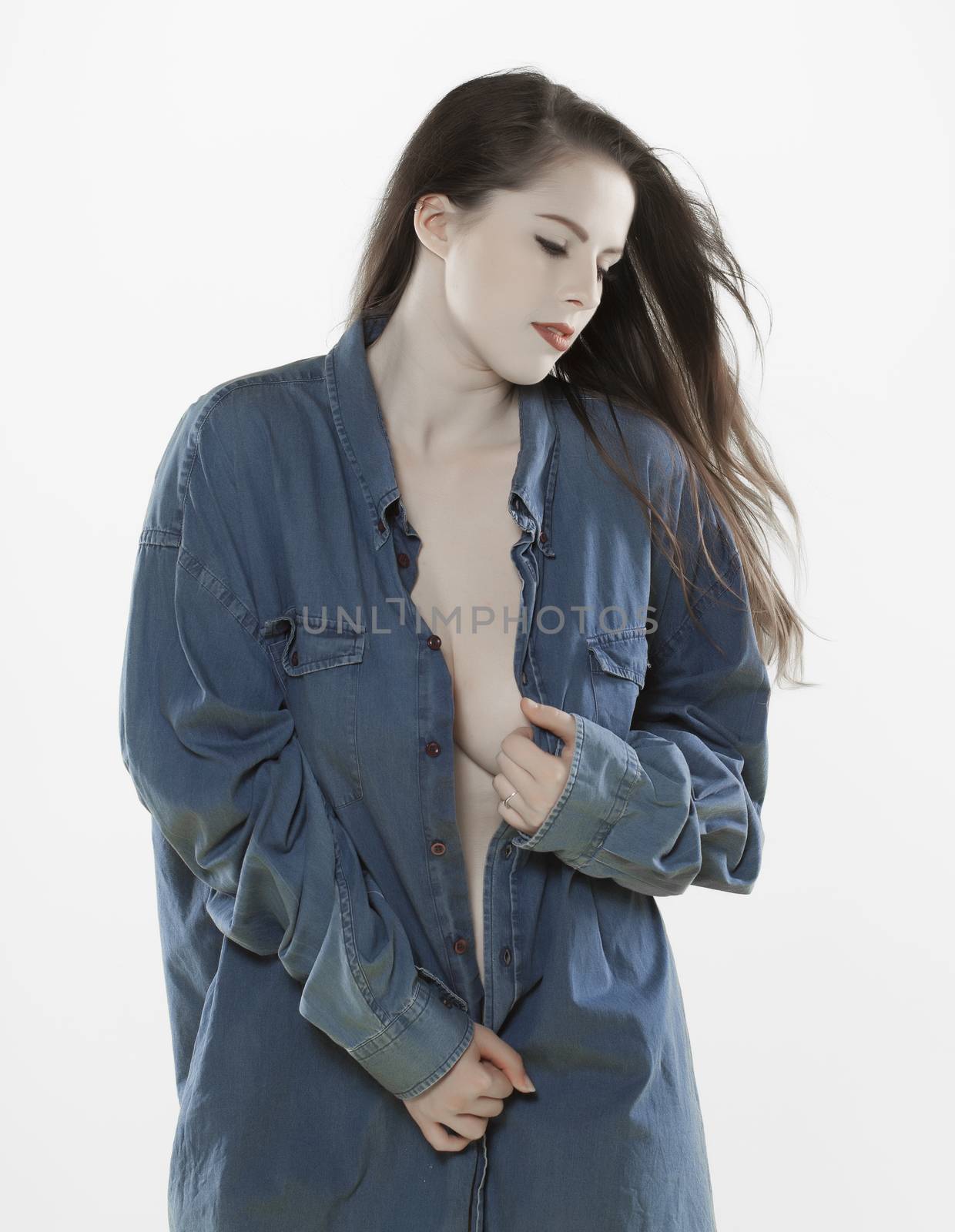 A beautiful fair skinned woman wearing a manes denim shirt over a light background.