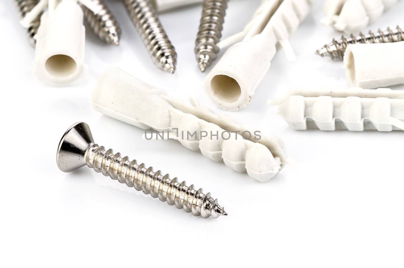Stainless steel screw and plastic dowel on white background