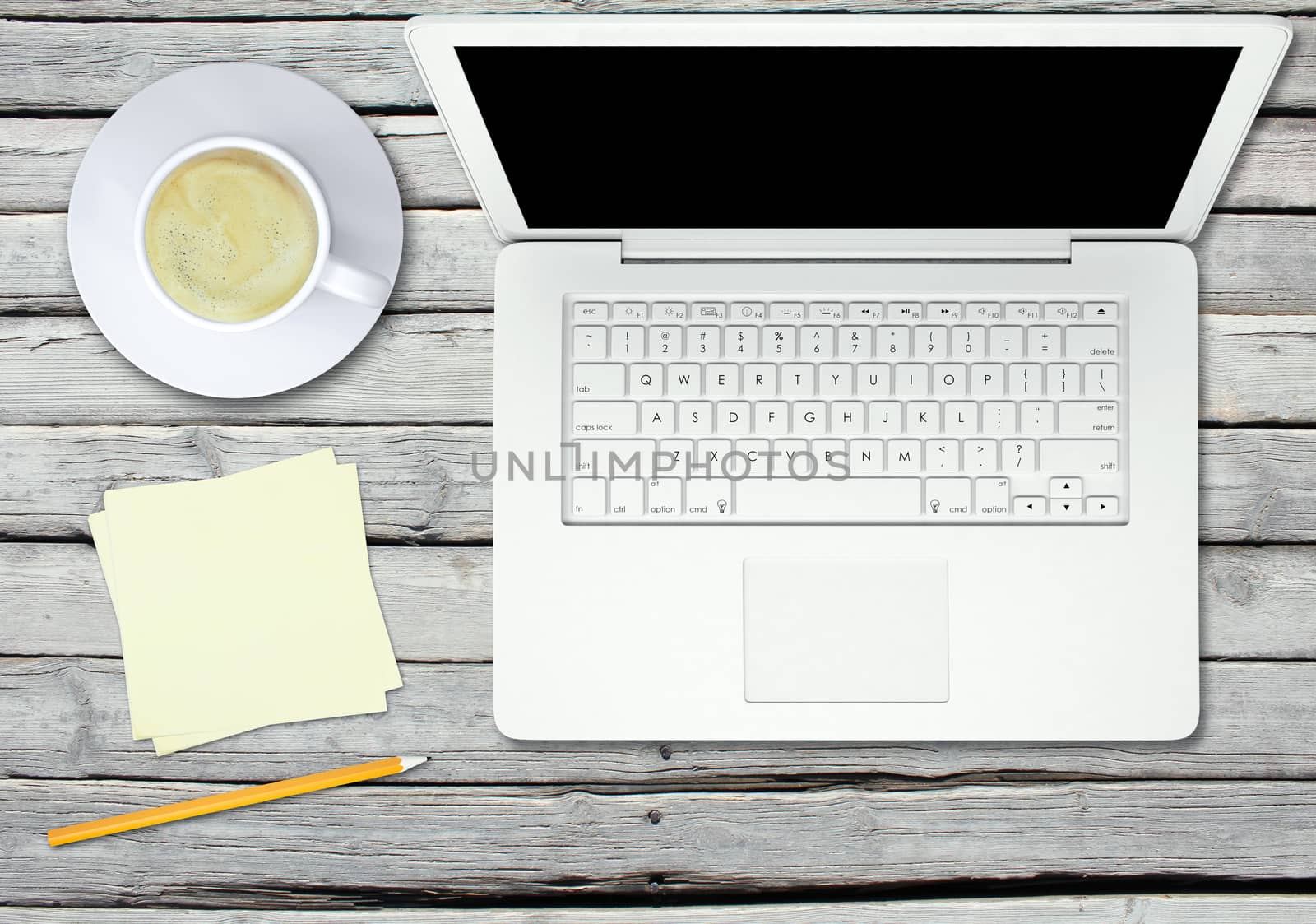 Laptop with cup of coffee and pencil on wood table