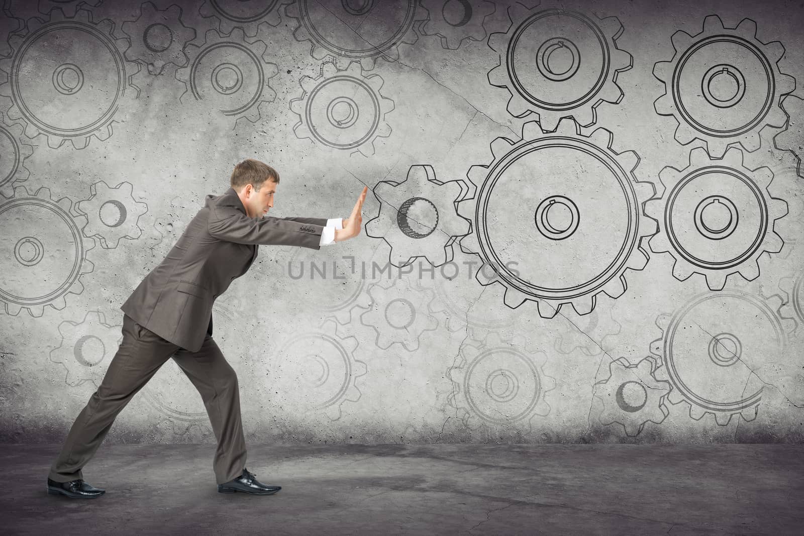 Businessman pushing cog wheels on abstract background