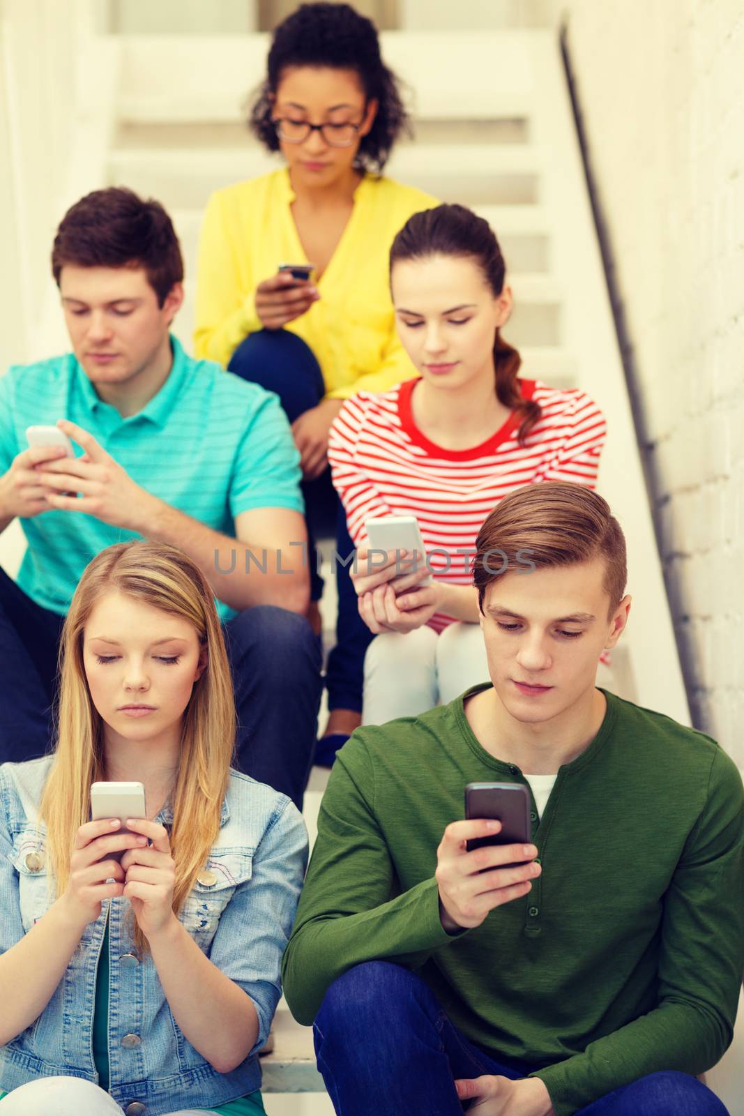 busy students with smartphones sitting on stairs by dolgachov