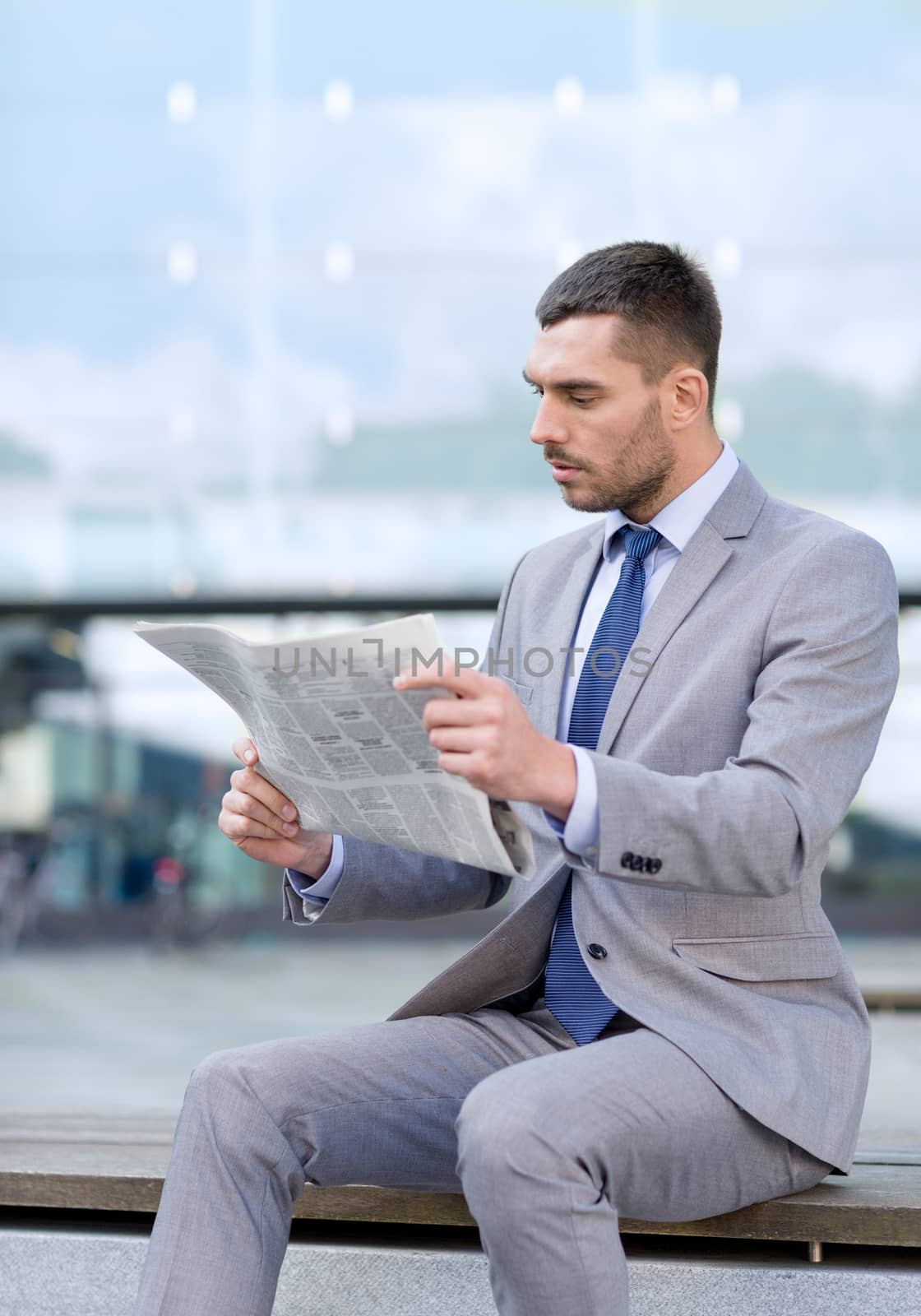 business, hot drinks and people and concept - young serious businessman with newspaper over office building