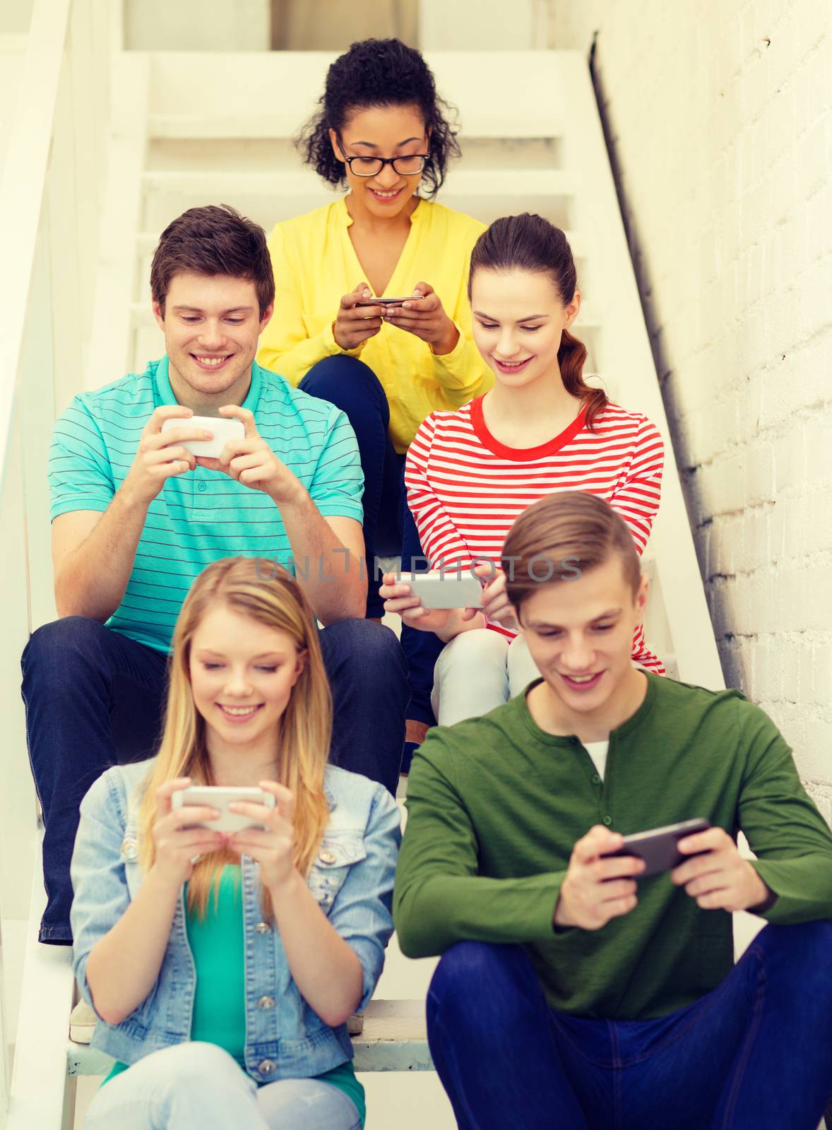 smiling students with smartphone texting at school by dolgachov