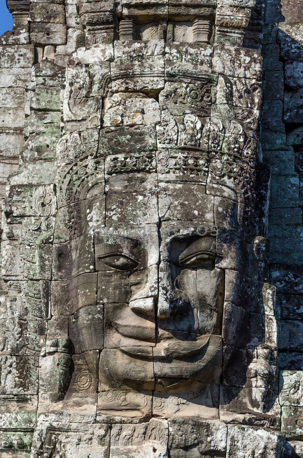 Ancient stone face of Bayon temple in Angkor Thom by siraanamwong
