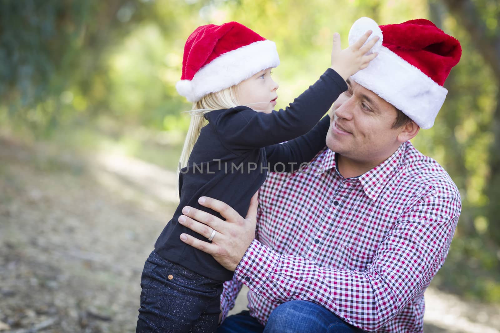 Father and Daughter Having Fun Wearing Santa Hats by Feverpitched