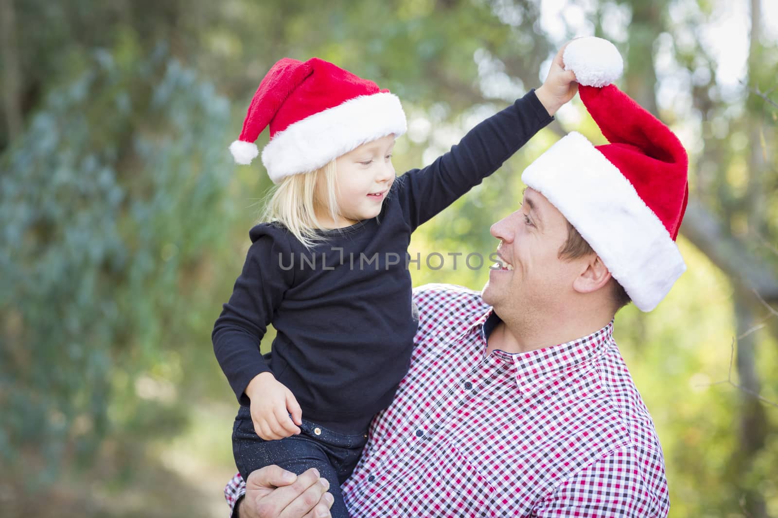 Father and Daughter Having Fun Wearing Santa Hats by Feverpitched