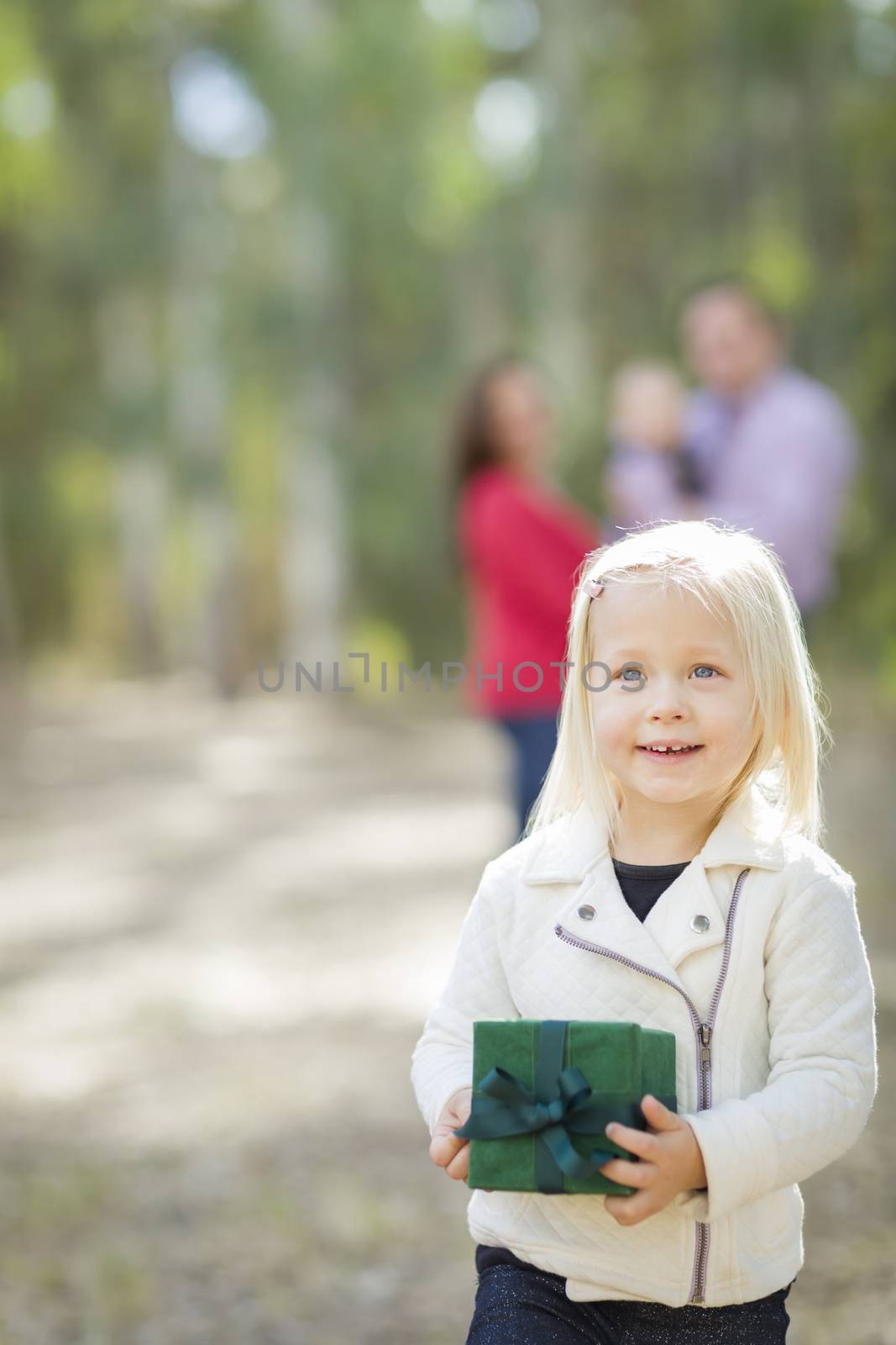 Baby Girl With Christmas Gift Outdoors Parents Behind by Feverpitched