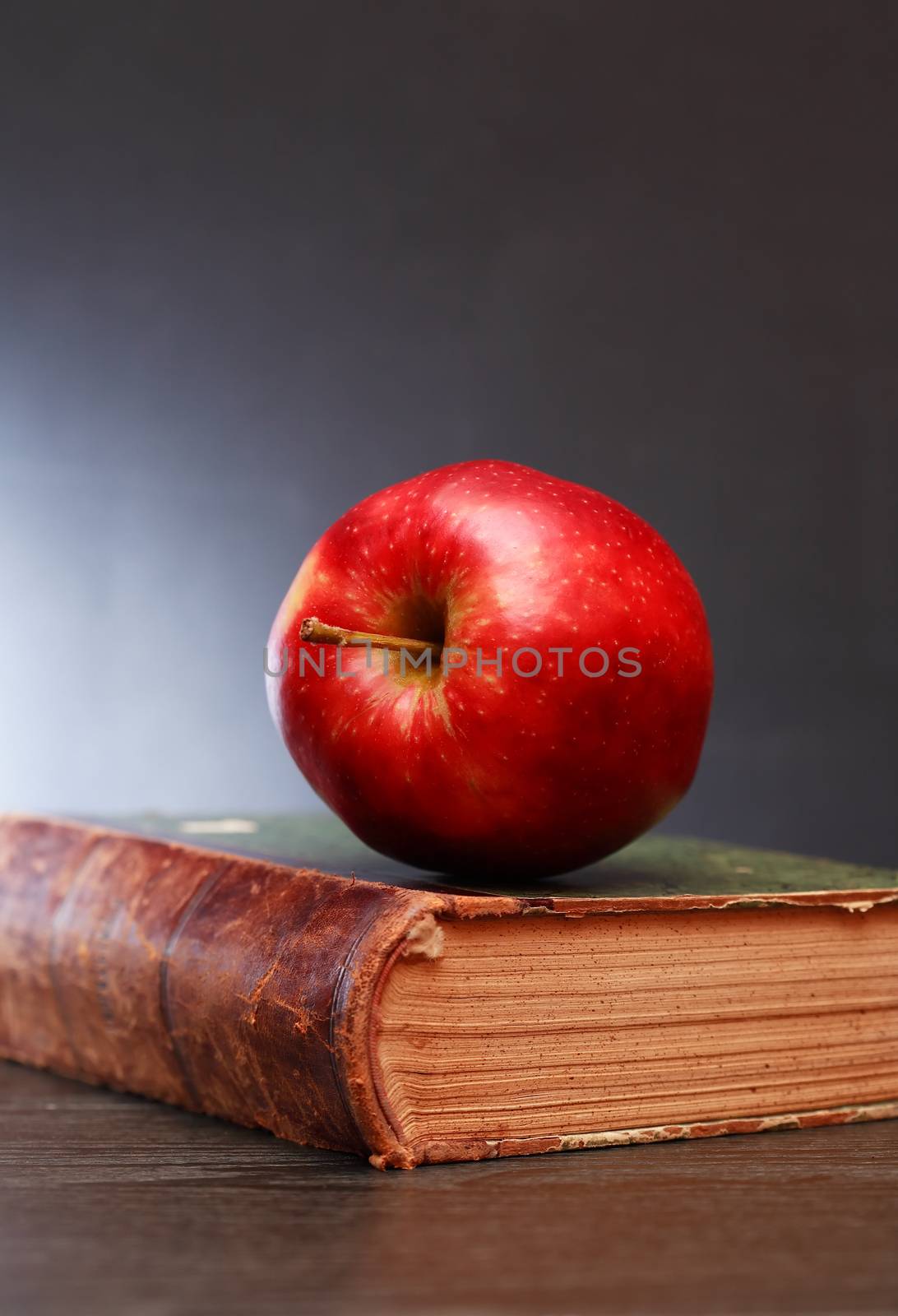 Freshness red apple on old book against dark background