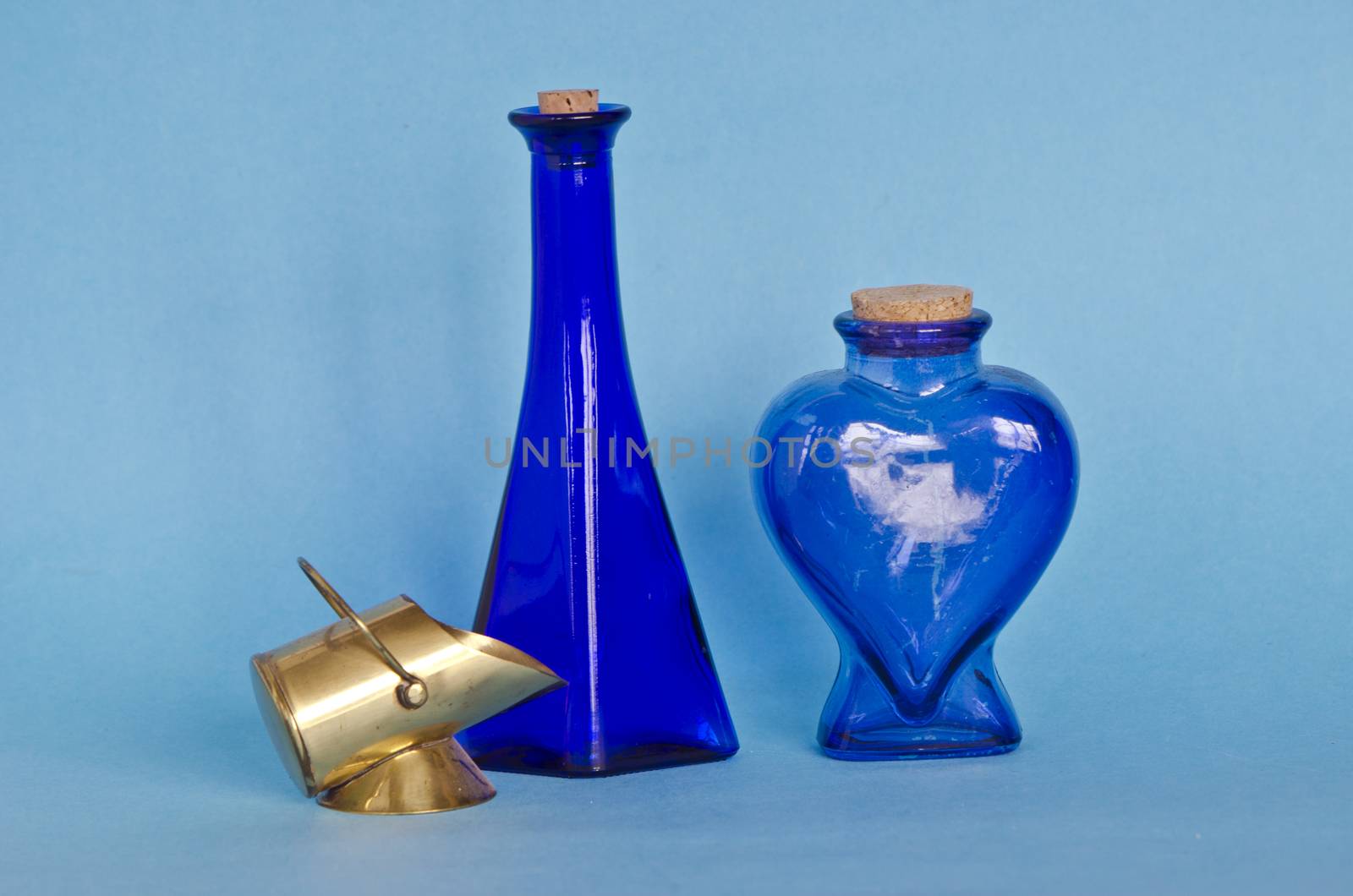Two blue glass bottles with decorative brass object by alis_photo