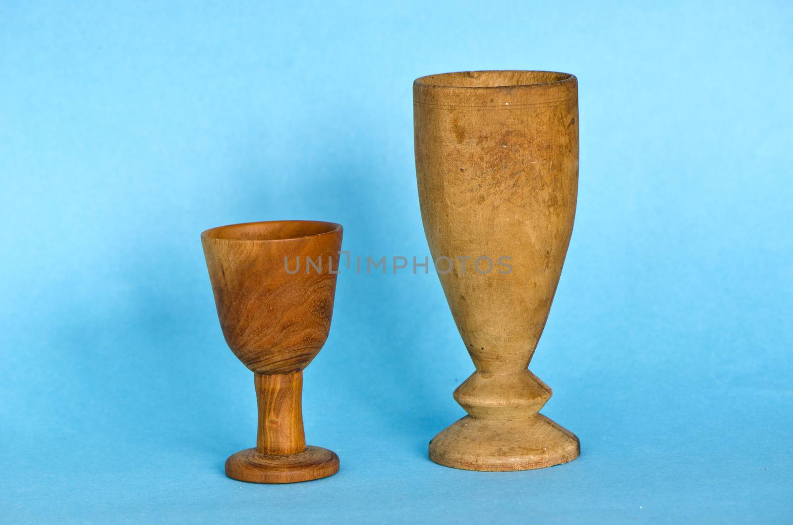Two wooden antique handmade glasses cup on blue background