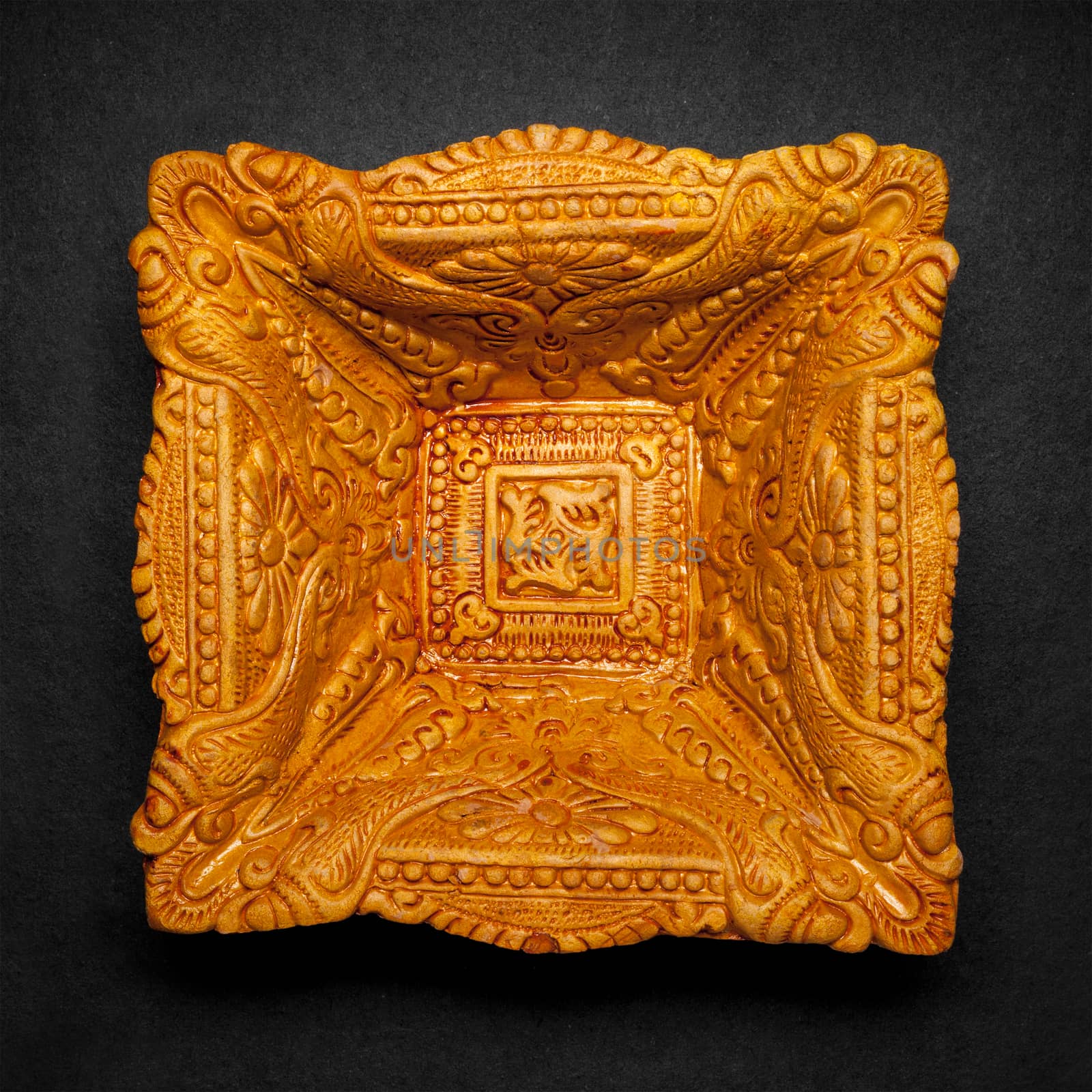Top view of a beautifully carved designer handmade clay lamp on dark background.