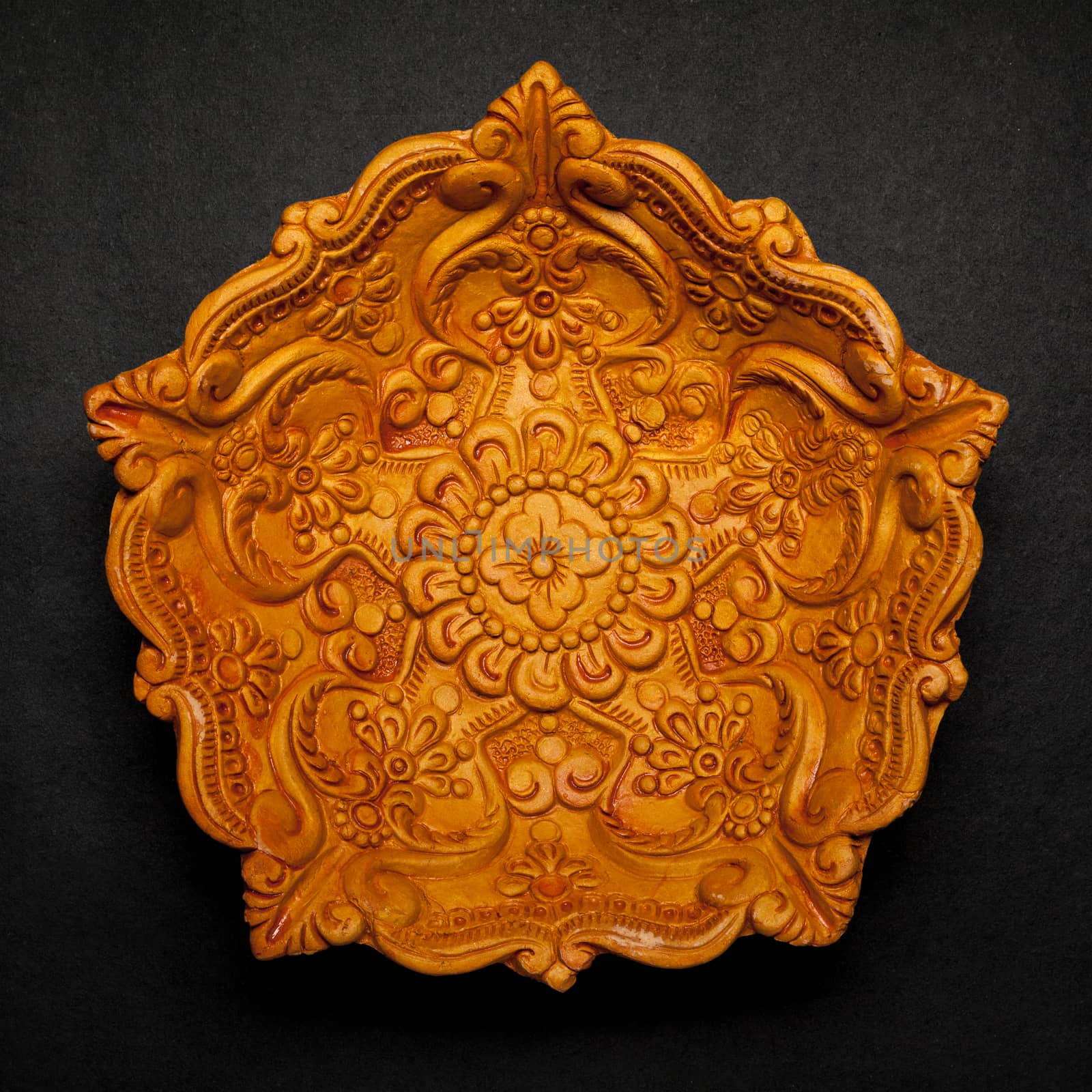 Top view of a beautifully carved designer handmade clay lamp on dark background.