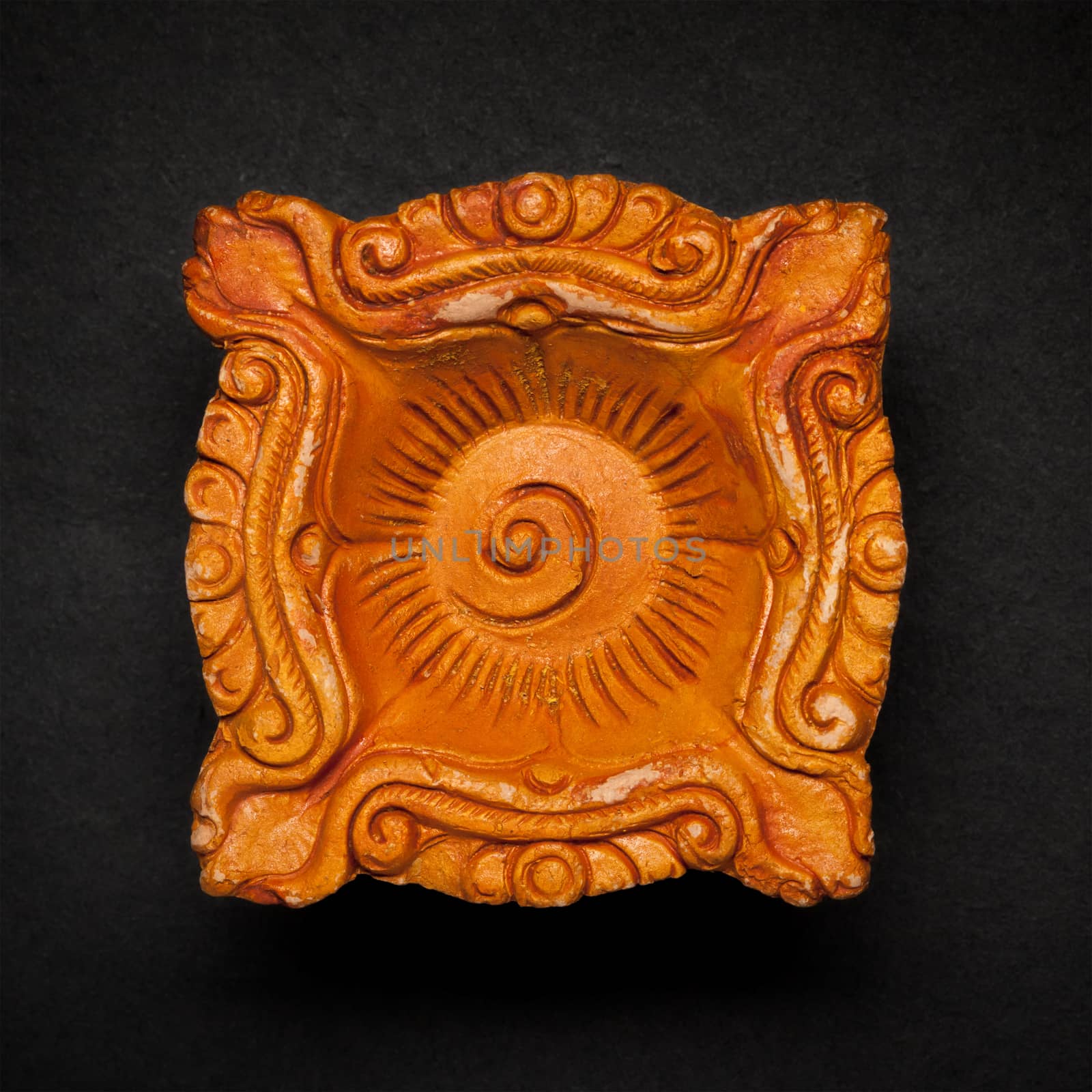 Top view of a beautifully carved designer handmade clay lamp on dark background.