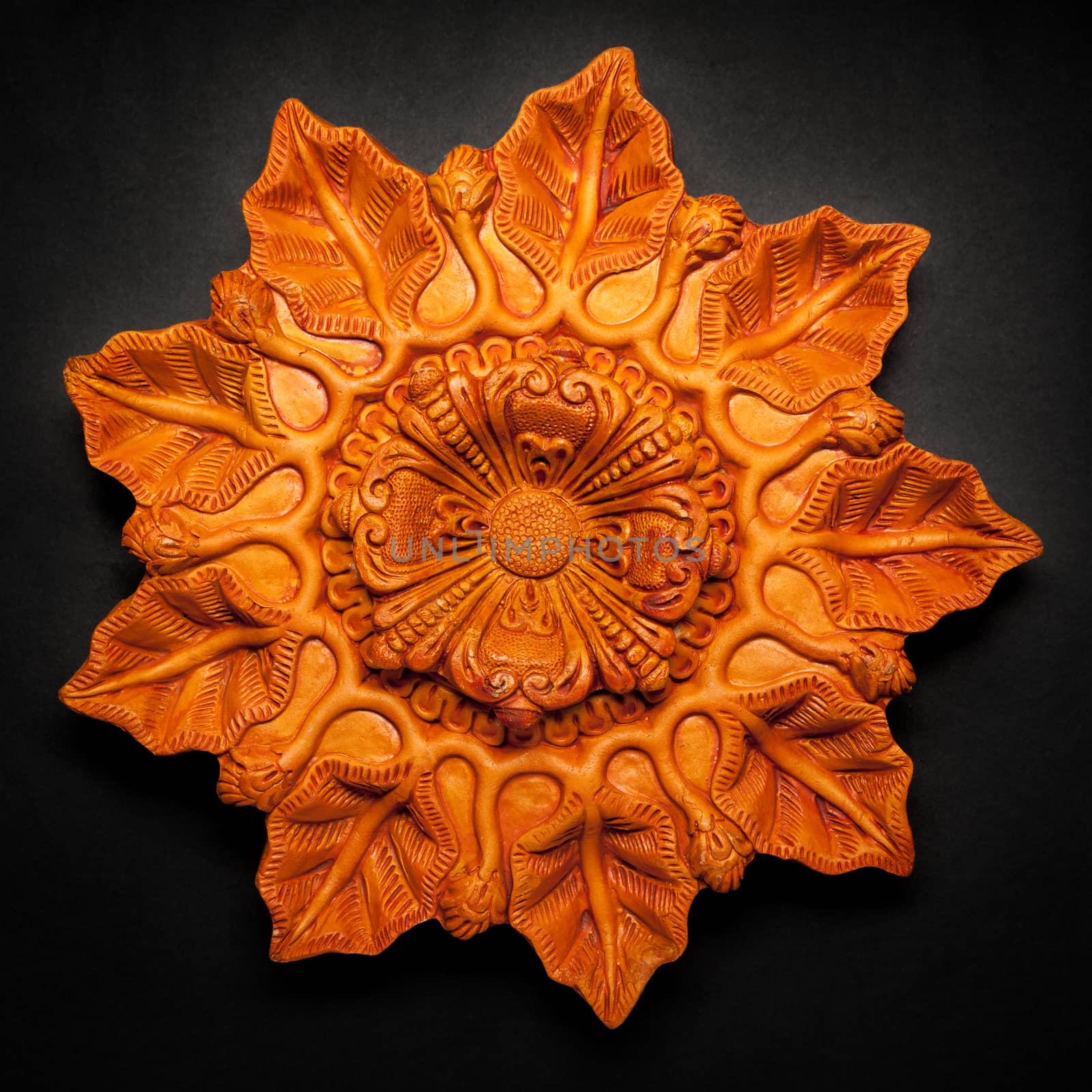 Top view of a beautifully carved designer handmade clay lamp on dark background.