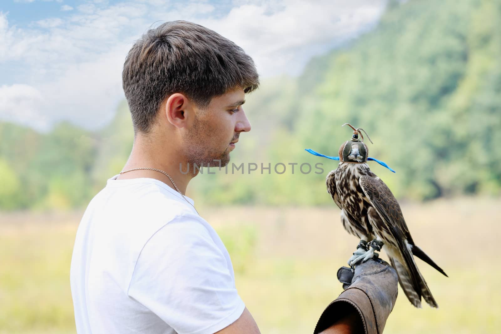 Young handsome man holding a falcon on his arm