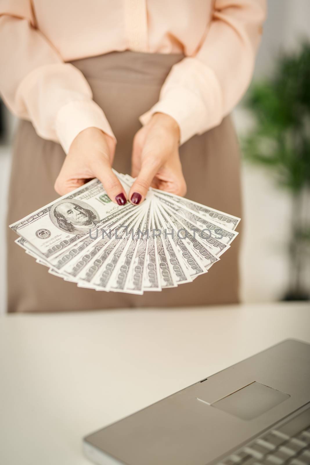 Unrecognizable businesswoman in outstretched hands holding dollar banknotes. Focus on the money.