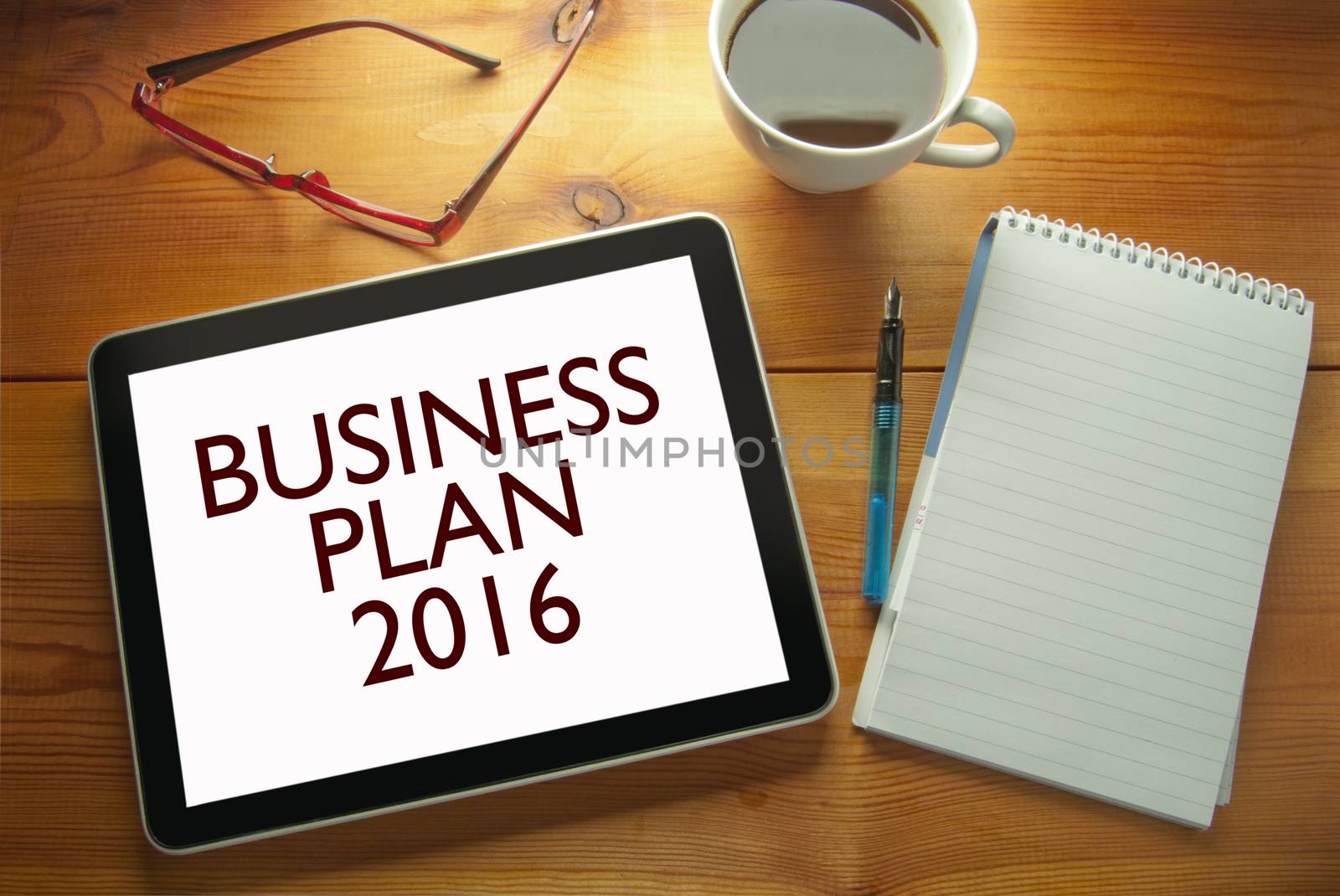 Work desk with computer tablet document entitled business plan 2016 