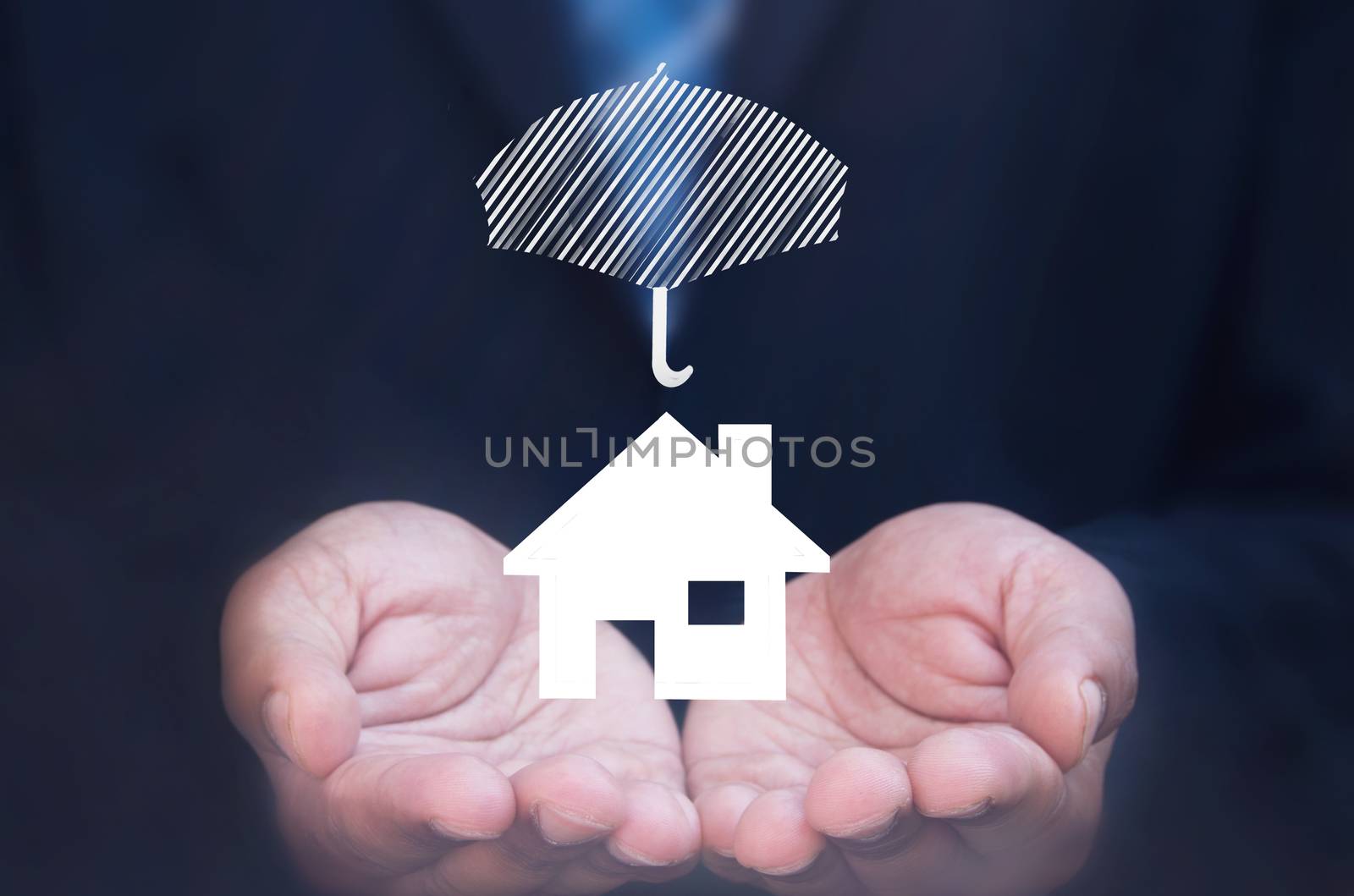 Business man holding a house icon protected by an umbrella 