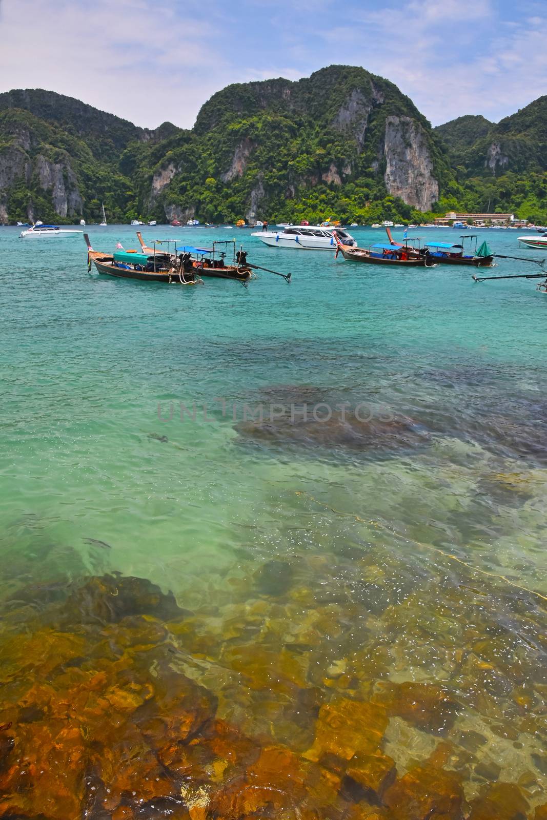 Paradise tropical sunny stone sea bay with sky blue green water and boats