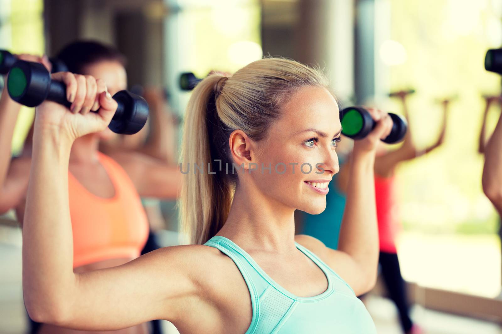 group of women with dumbbells in gym by dolgachov