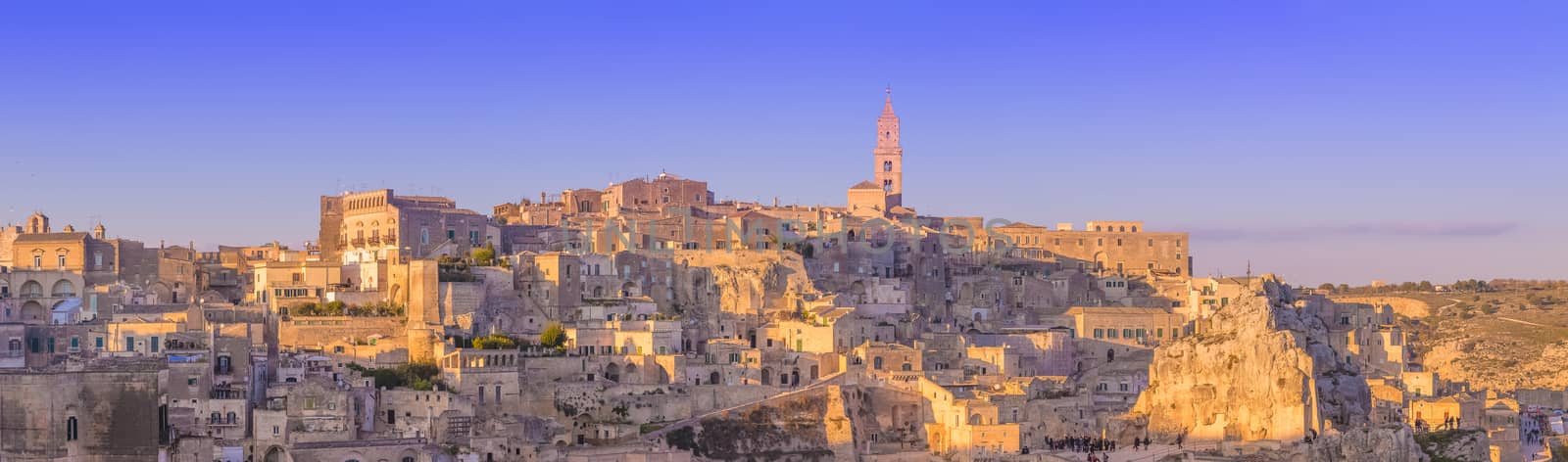 panoramic view of typical stones and church of Matera and the Madonna de Idris under begin sunset sky by donfiore