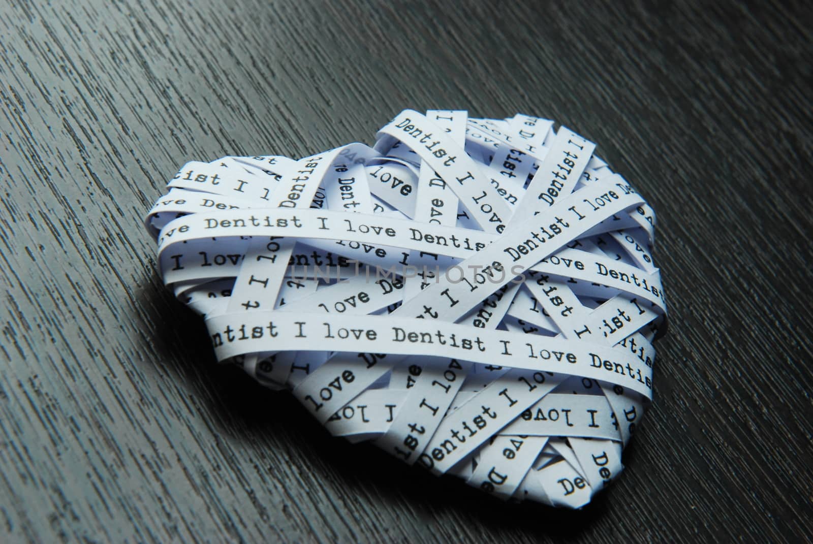 White paper ribbon in heart shape showed text 'I love dentist' on dark background