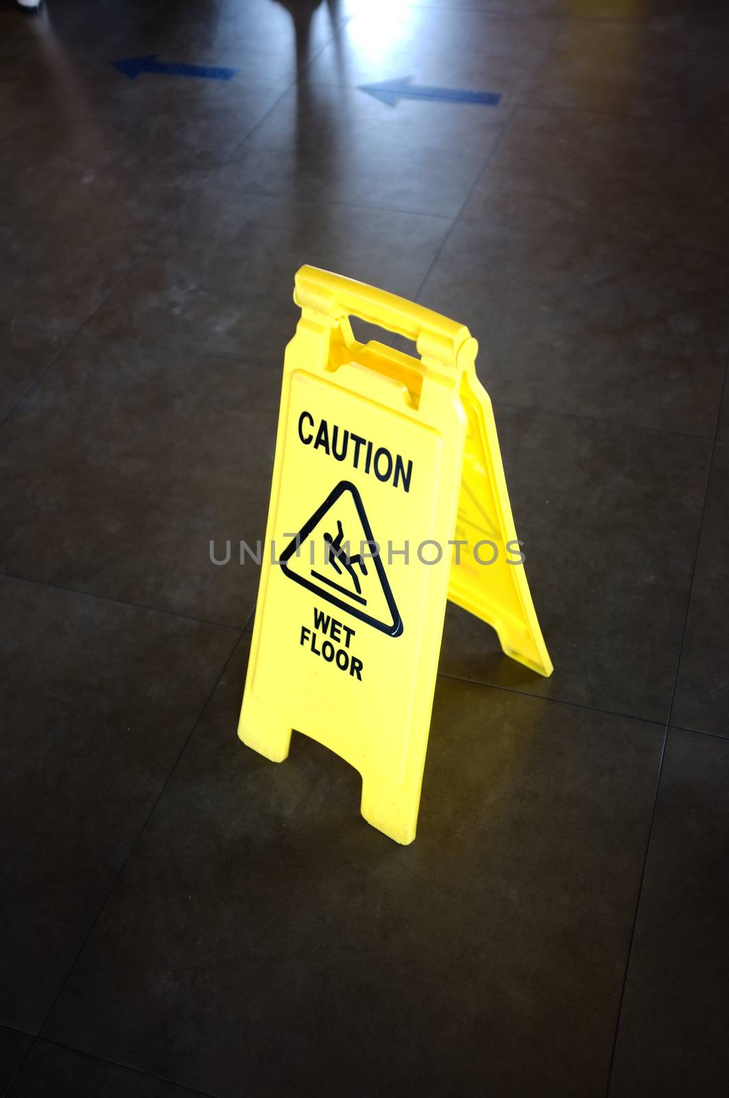 Caution yellow sign for wet floor warning on a floor by Hepjam