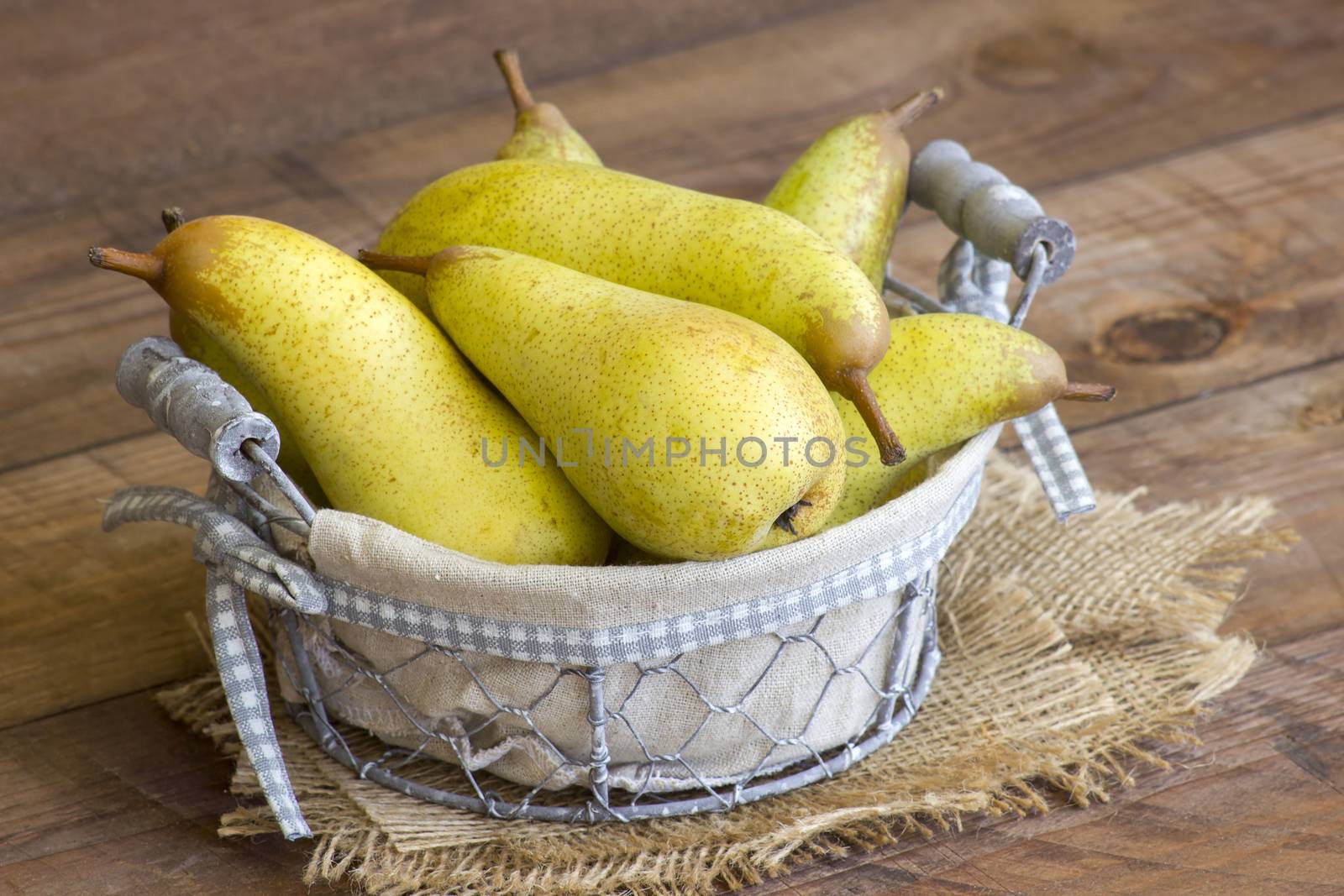 Juicy fresh pears in a basket on dark wooden background