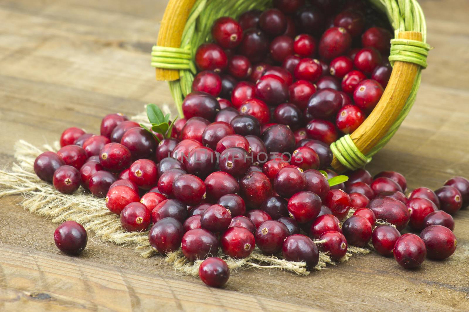 Cranberries in a basket on wooden background.